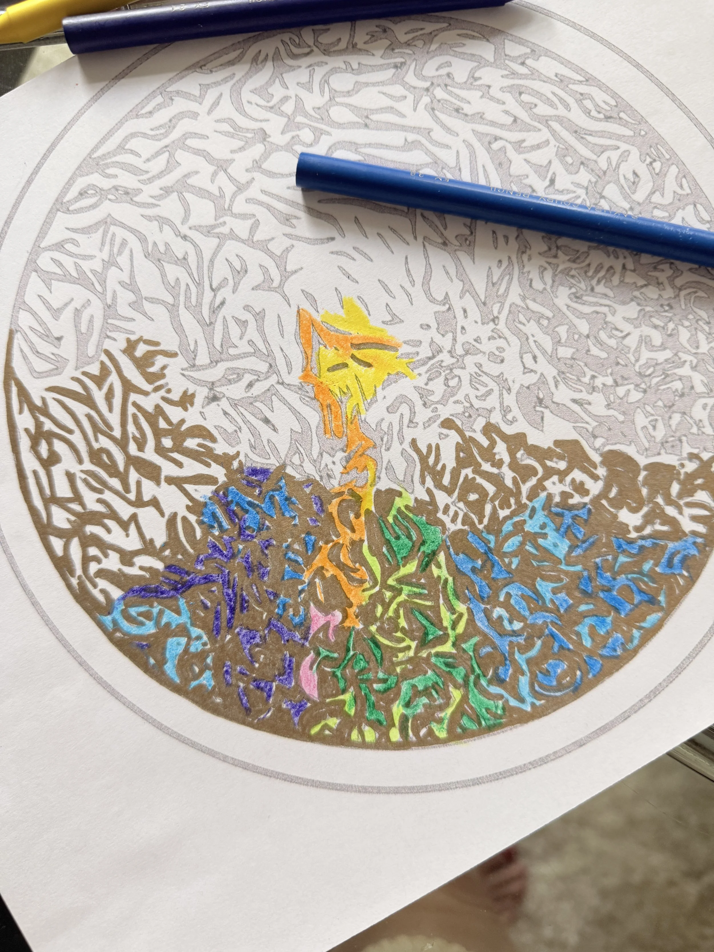 A person is coloring a mandala with yellow tulips in the center, surrounded by black and white intricate patterns. The workspace includes a salt lamp, a potted plant, watercolors, brushes, and a glass of tea on the table.