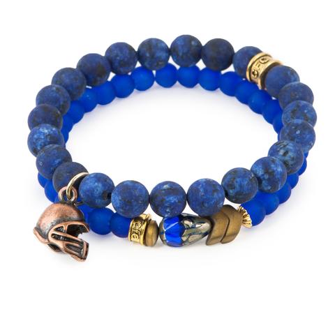Team Spirit (Set of Two) Blue dyed jade and glass bracelet set of two with Czech glass accent, antique bronze-tone hematite detail, and copper-tone helmet charm. Measures approximately 7.5" in length. With the purchase of this bracelet set, 25% of gross profit goes to Water.org. All bracelet sets come with a pouch and a hang-tag detailing the mission of each charity. 