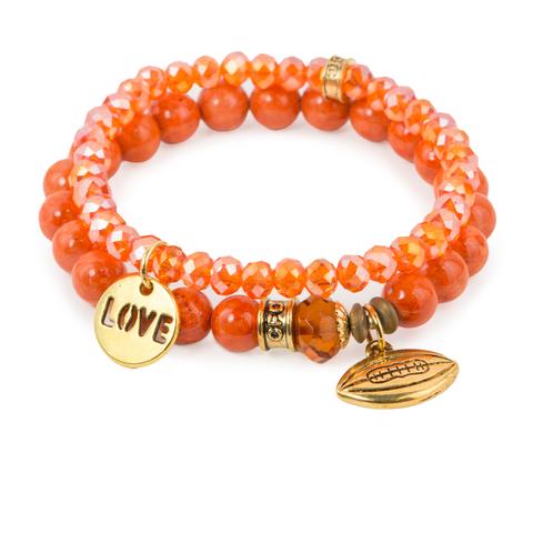 Love Football (Set of Two) Orange fossil and crystal glass bracelet set of two with Czech glass accent, gold love, and football charms. Measures approximately 7.5" in length. With the purchase of this bracelet set, 25% of gross profit goes to Best Friends Animal Society. All bracelet sets come with a pouch and a hang-tag detailing the mission of each charity. 