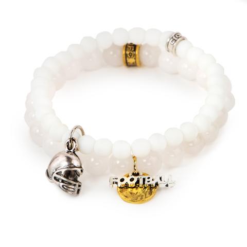 Game On! (Set of Two) White dyed jade bracelet set of two with mixed metal football charms. Measures approximately 7.5" in length. With the purchase of this bracelet, 25% of gross profit goes to the Matthew Shepard Foundation. All bracelet sets come with a pouch and a hang-tag detailing the charity's mission. 