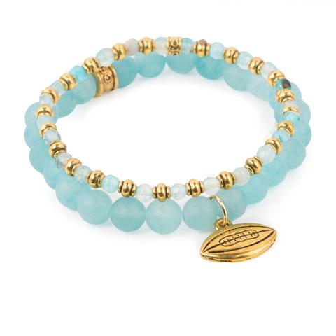 Catch the Spirit (Set of Two) Blue agate and dyed jade bracelet set of two with gold-detail and football charm. Measures approximately 7.5" in length. With the purchase of this bracelet set, 25% of gross profit goes to Water.org. All bracelet sets come with a pouch and a hang-tag detailing the mission of each charity. 