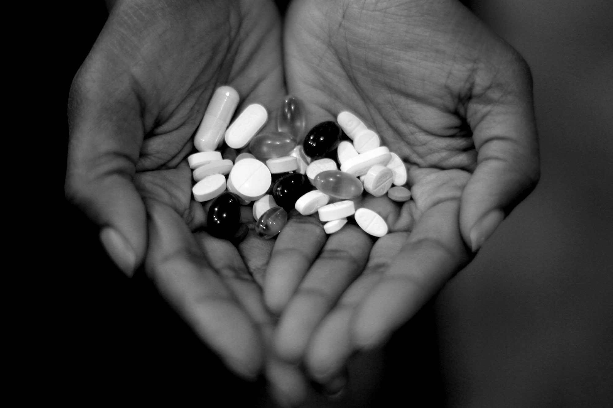 Mike's sister, Crystal Houston, holds the 30 pills Mike needs to take every day, including painkillers, vitamins and antibiotics. 