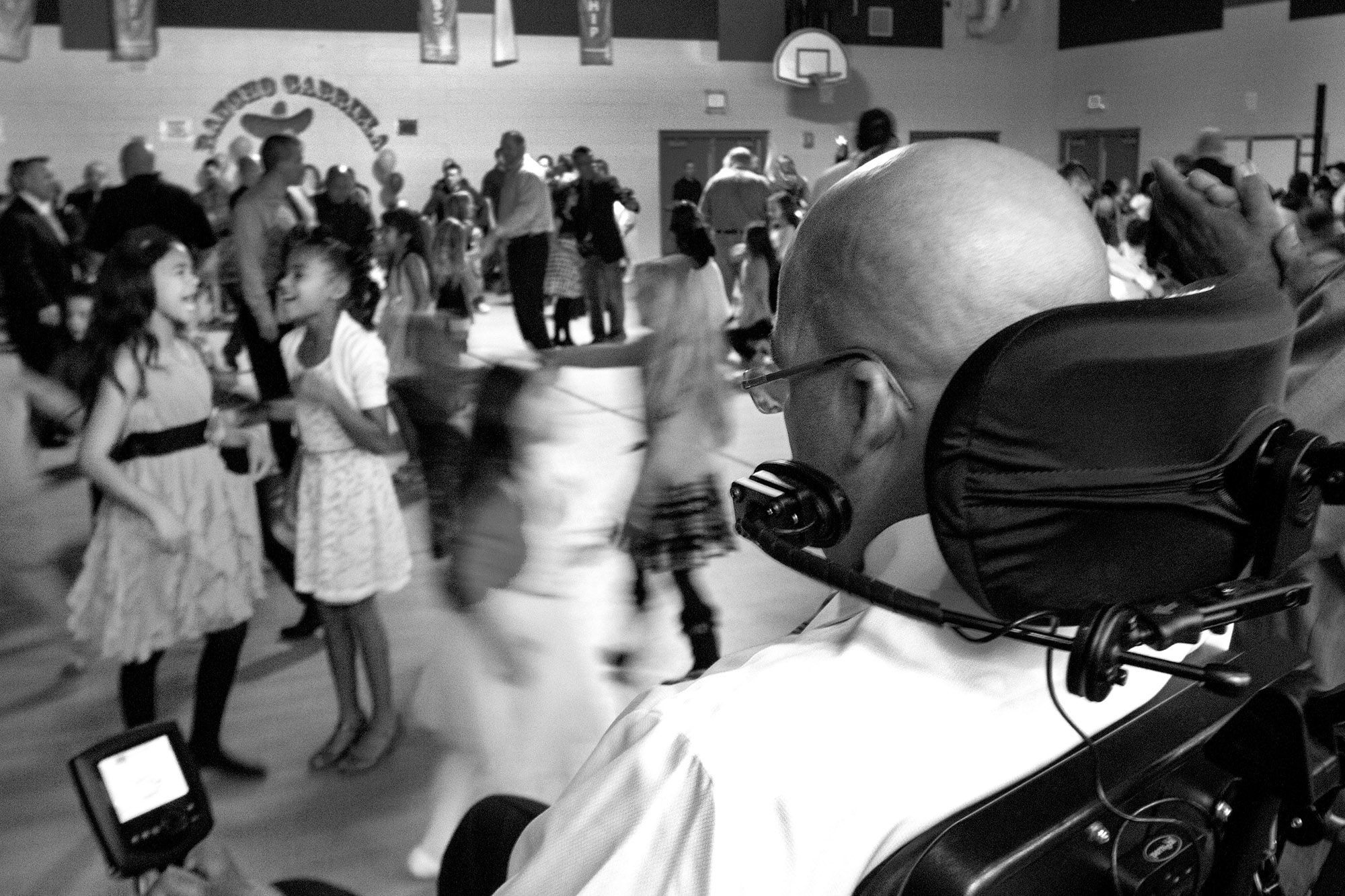  Mike watches his daughter Miah (left)&nbsp;laugh with her friend during a father-daughter dance in her school's gymnasium. 