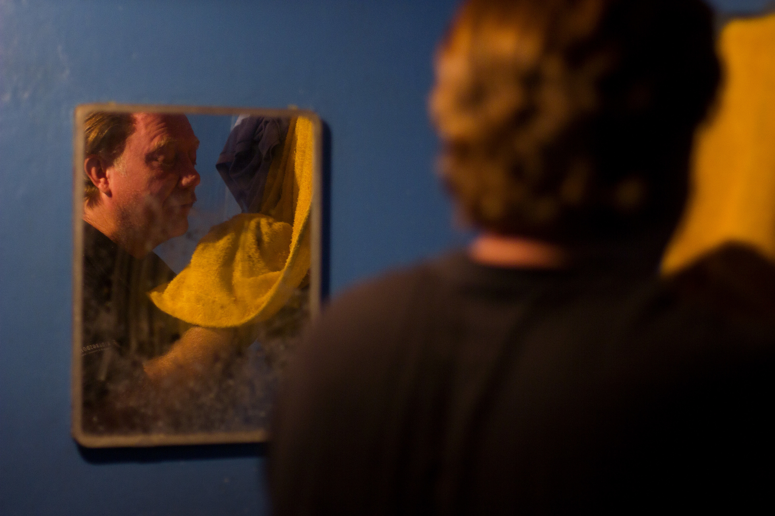 Virgil Edwards washes his face after getting sawdust in his eyes from the half-dozen trees he trimmed that morning. He is alone in trying to rebuild the land — his brother lives in the United States and his neighbors remain wary of a future invasion.