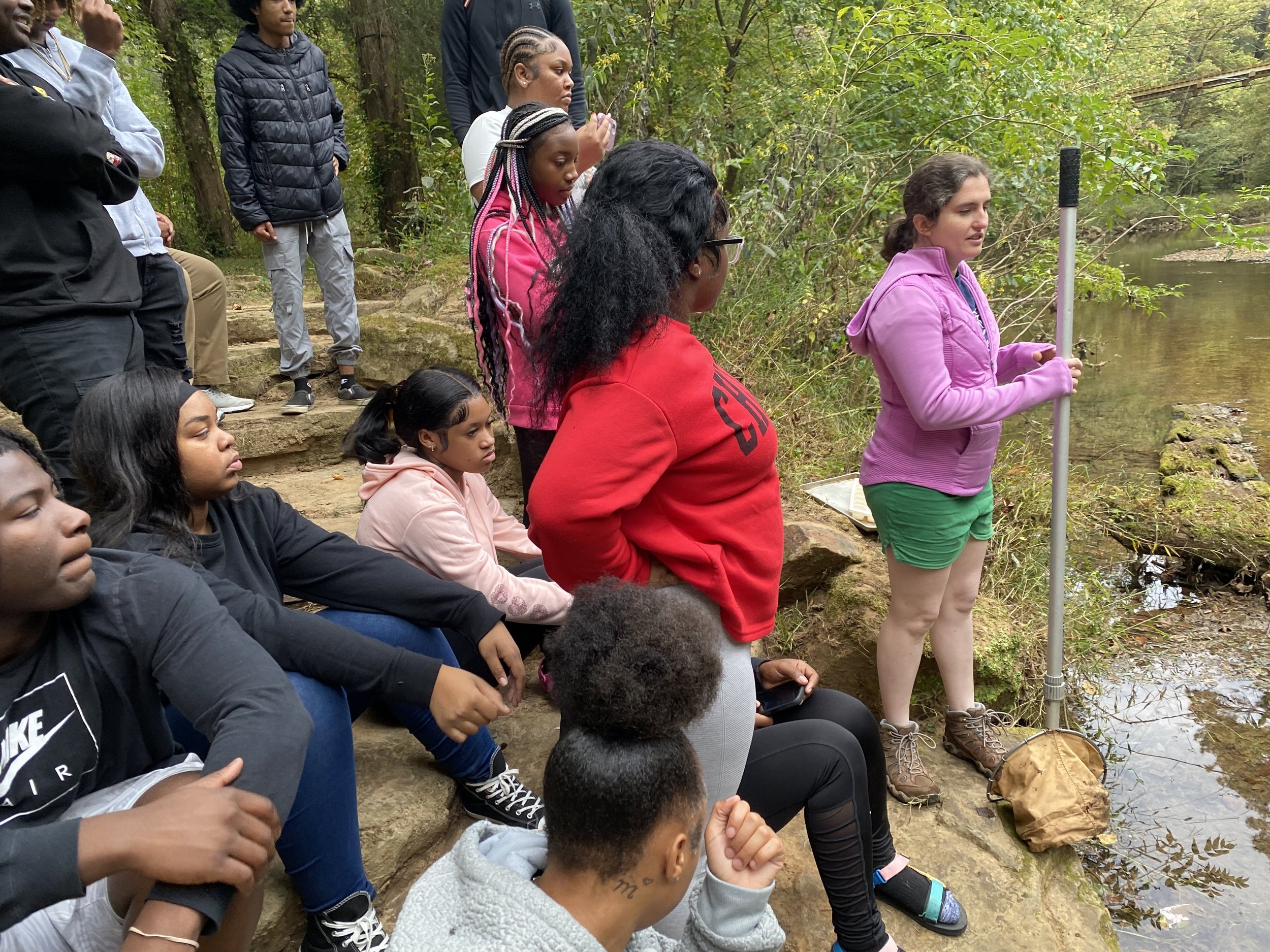    Students from Birmingham City Schools in partnership with Jefferson County Health Department watch as Emily, Wildlife Care Naturalist, demonstrates how to dip-net for aquatic macroinvertebrates. Together we hosted 83 educational programs serving 4