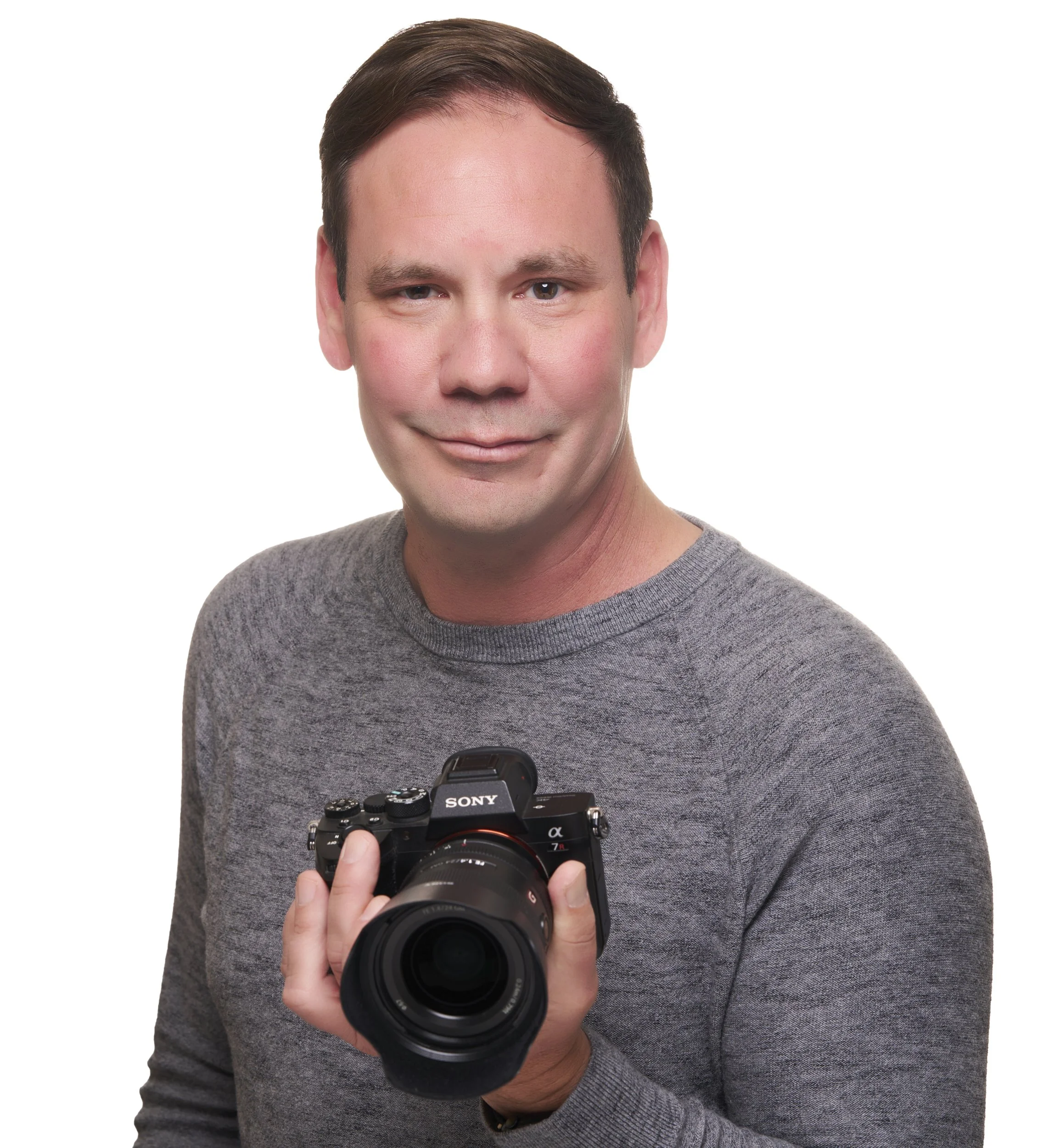 Jason Collin professional PG photographer in studio wearing a sweater holding his camera