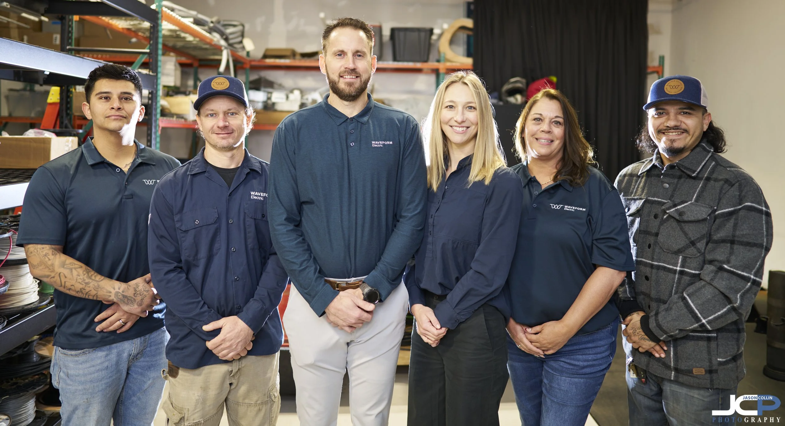 On-location team photo of six Waveform employees in Pacific Grove warehouse showing coordinated professional portraits.