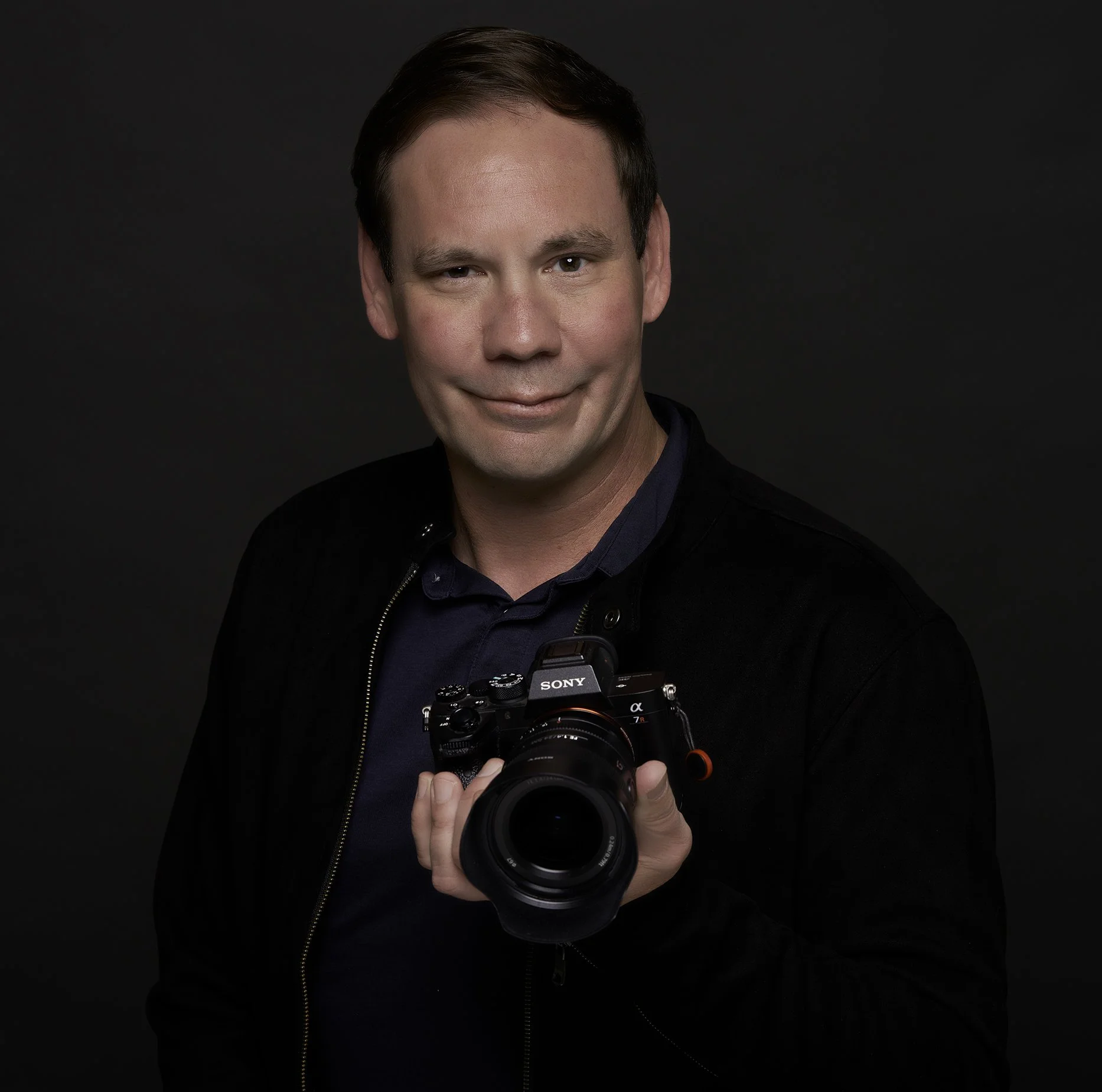 Professional Photographer Jason Collin holding a camera in his Pacific Grove studio