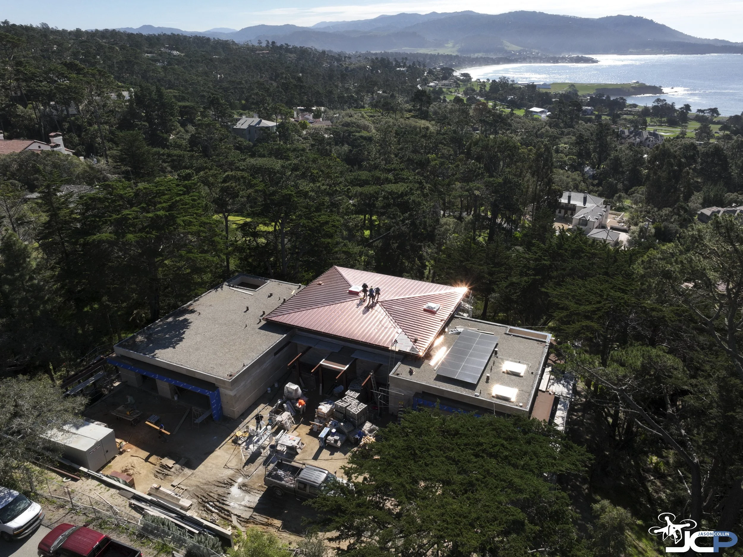 Drone aerial view of a luxury Pebble Beach residential construction project highlighting copper roofing and site progress.