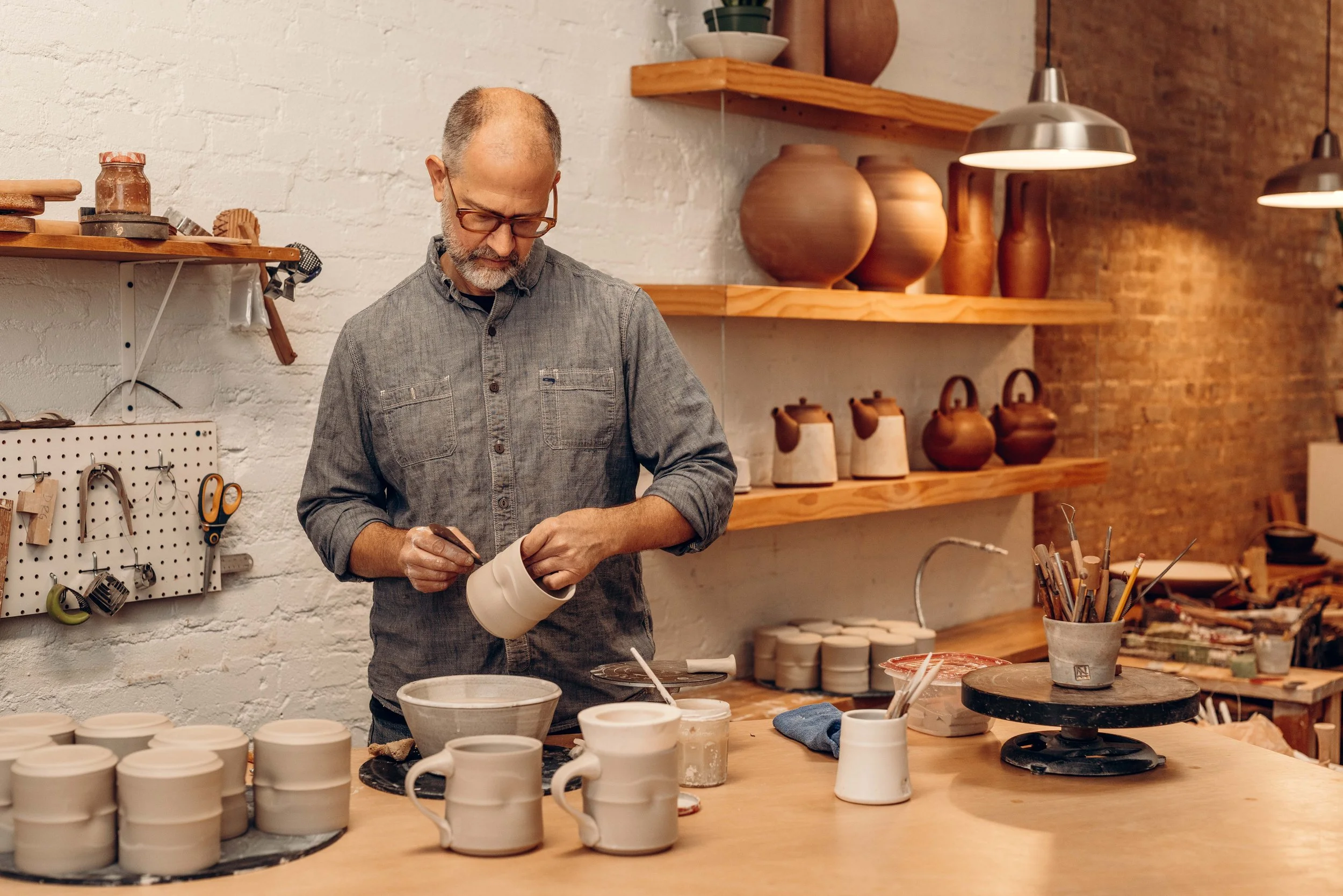 Potter creating porcelain mugs in studio.