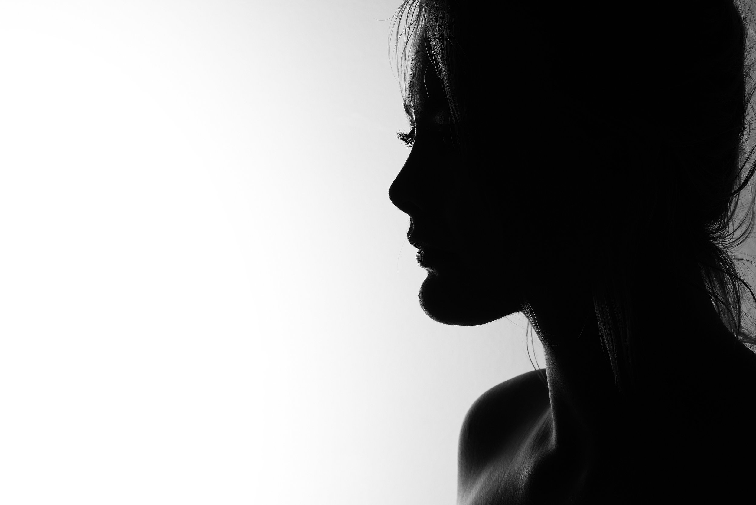 Silhouette of a woman with her hair tied up, looking to the right, against a white background. Photography by Kenneth Dolin, top Los Angeles headshot photographer. 