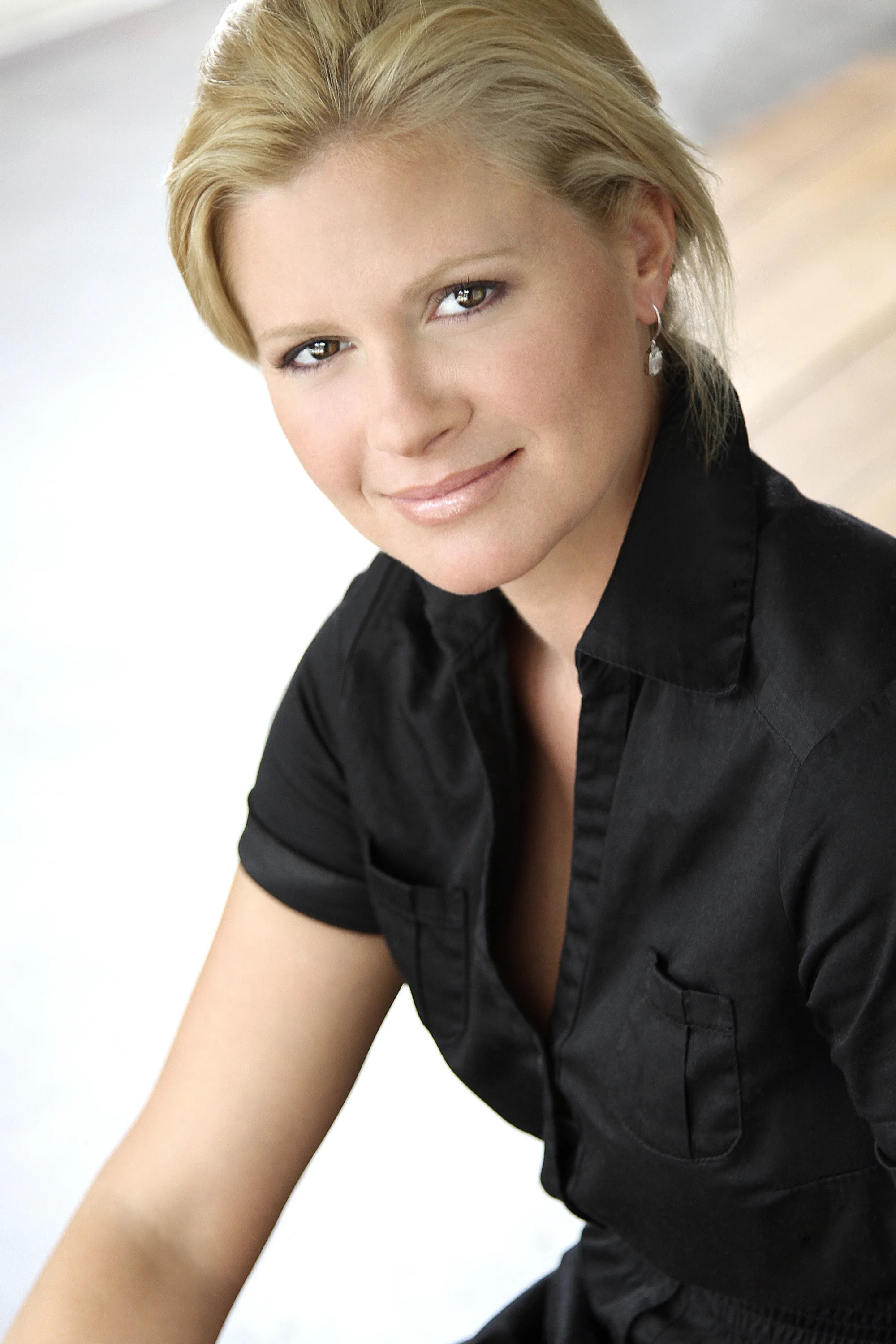 A woman with blonde hair, wearing a black shirt, smiling at the camera.