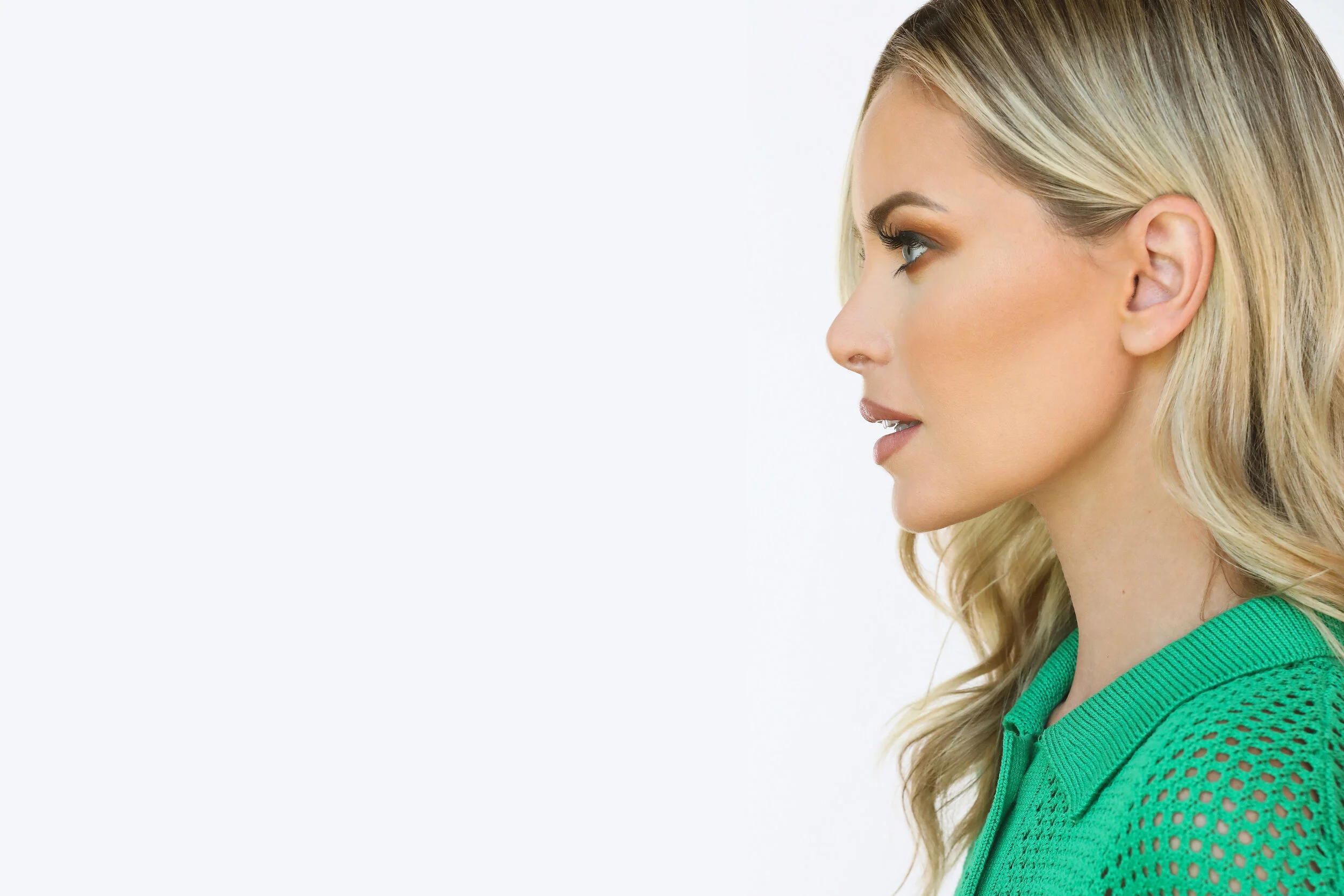 Side profile of a young woman with blonde hair, fair skin, and wearing a green, mesh-style top.Model photographed by Los Angeles photographer Kenneth Dolin. Top Los Angeles photographer specializing in model photography, beauty photography and editor