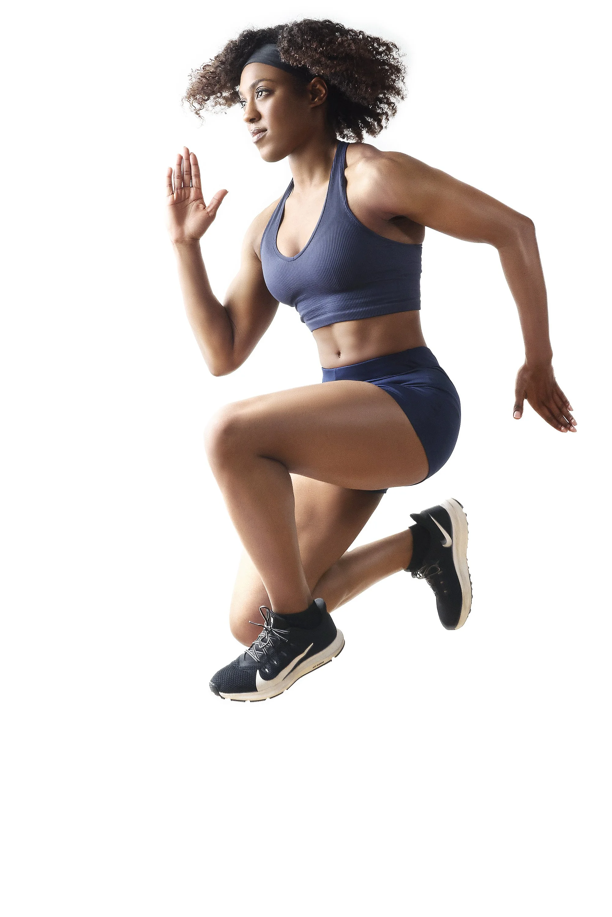 A woman with curly hair in sportswear running and jumping