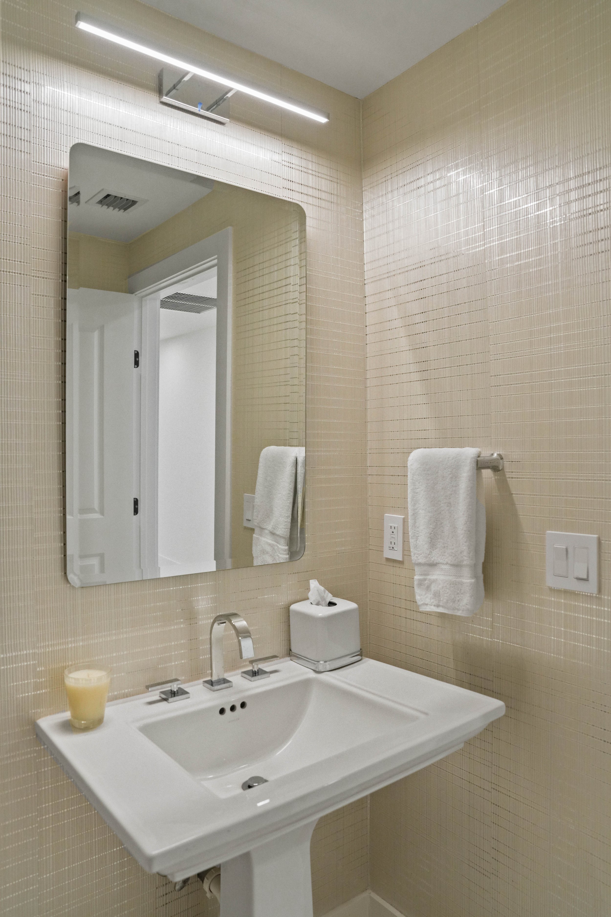 After Hillsboro Beach luxury powder room featuring textured porcelain wall tile, a floating vanity, contemporary chrome fixtures, and a refined spa-inspired design.