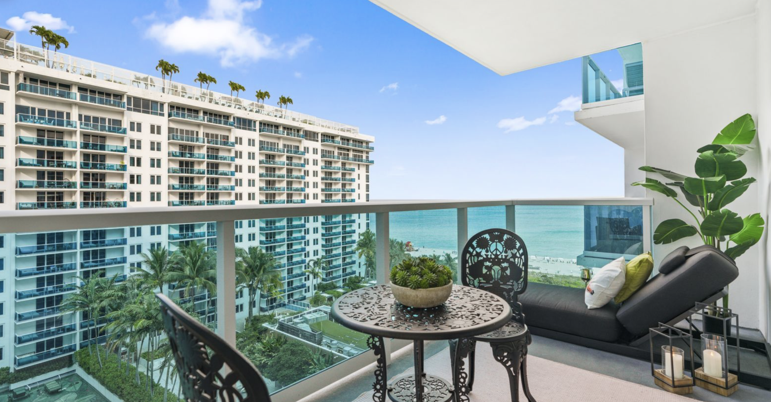 Miami Beach balcony with ocean view, decorative lounge seating, and whimsical-style outdoor table