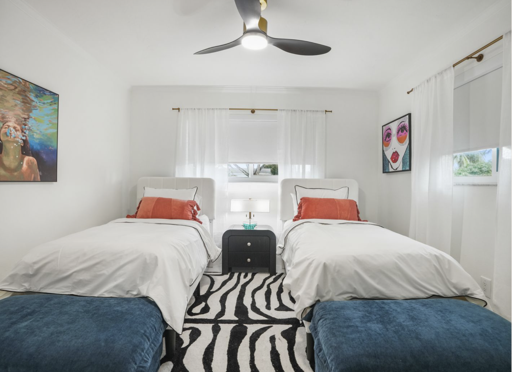 Twin guest bedroom in Miami vacation rental with upholstered beds, graphic rug, colorful artwork, blackout shades, and polished coastal styling.