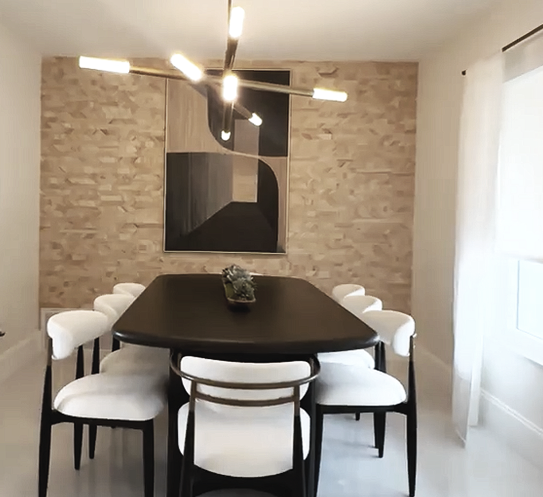 Dining room in Miami vacation rental with geometric plank table, soft upholstered chairs, sleek Sputnik-style chandelier, and textured wood wall covering.