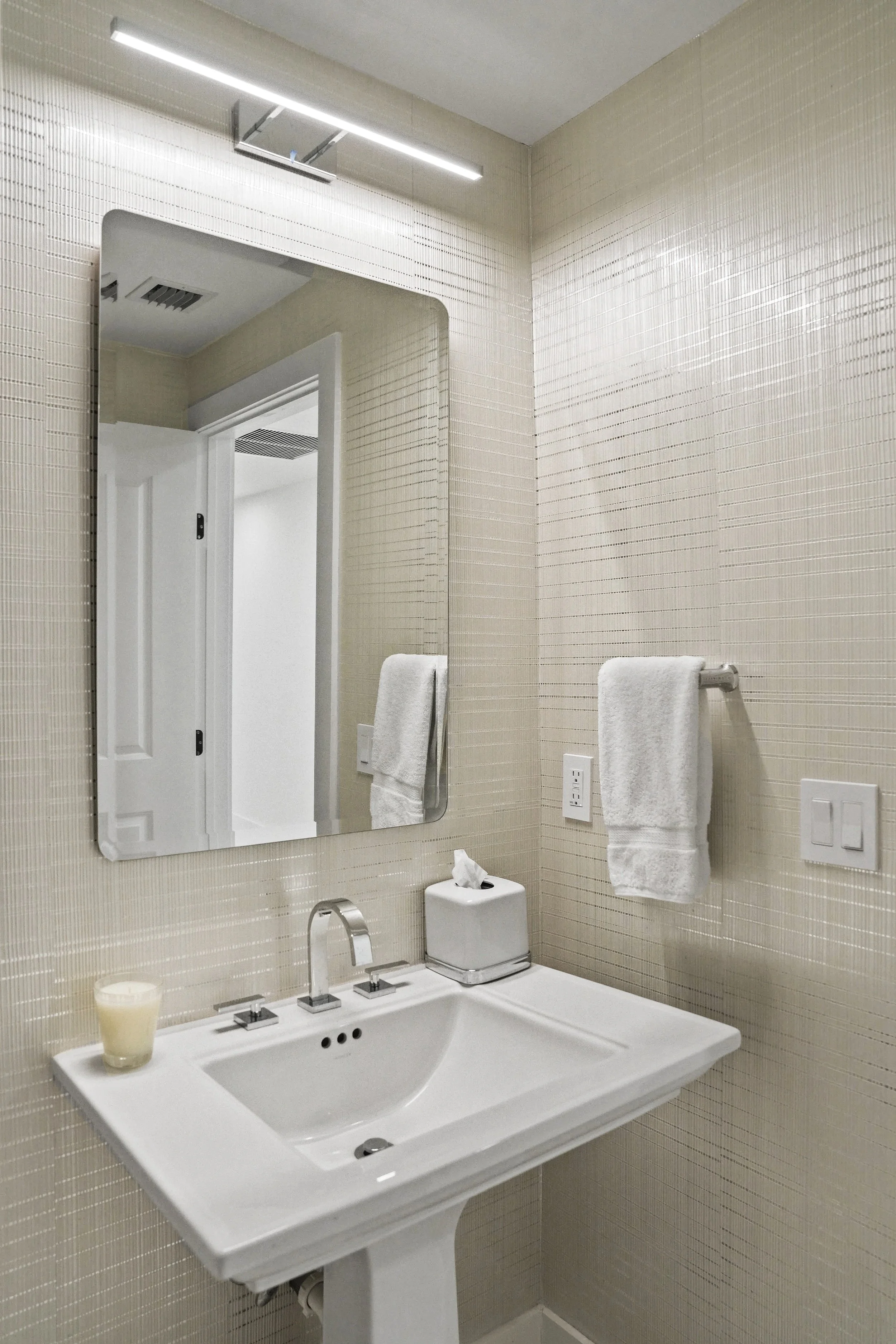 Classic powder room transformed with a custom white cross-rib wallcovering on reflective chrome foil, contemporary LED mirror, floating vanity, and sleek modern finishes that create a luminous, sophisticated retreat.