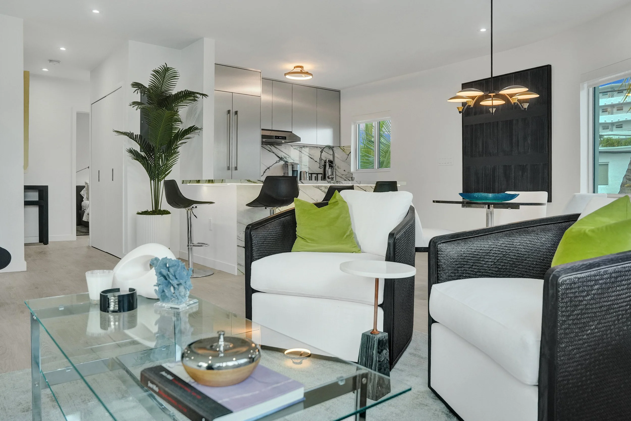 Miami Beach historic condo remodel with dramatic green Calacatta porcelain island and stainless steel kitchen opening to an urban coastal great room