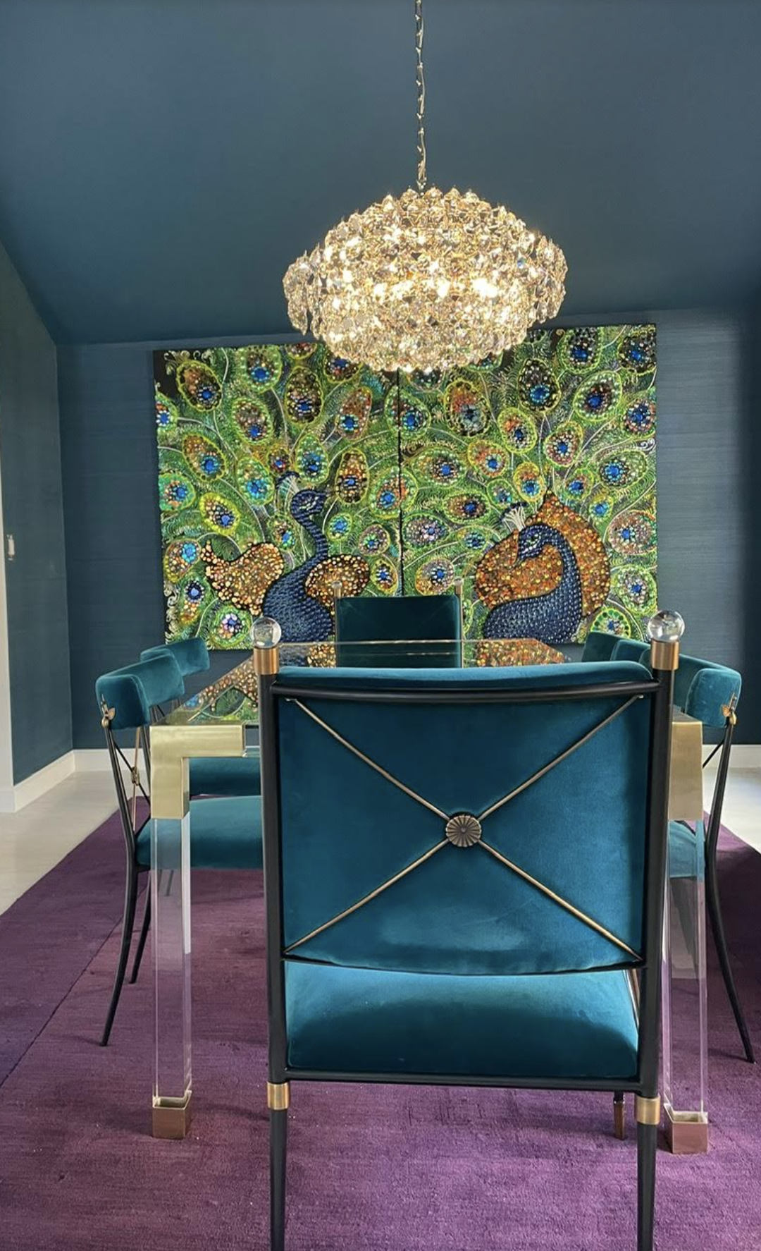 Upscale South Florida dining room design featuring a custom jewel-encrusted peacock artwork diptych, deep teal abaca wall covering, and a luxury modern Jonathan Adler dining table set.