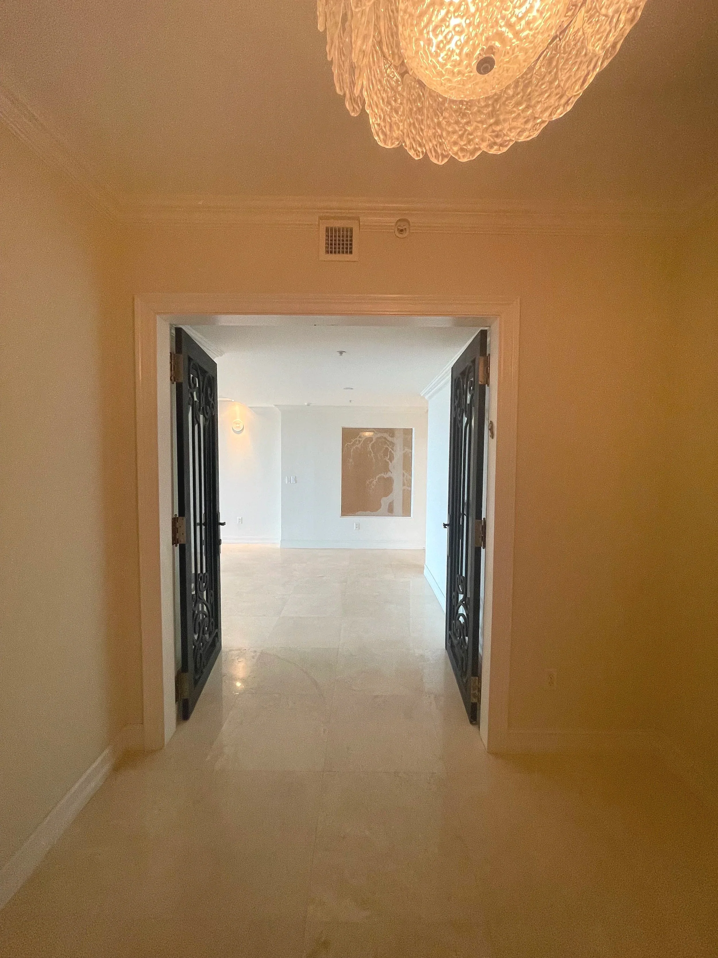 Before renovation of Hillsboro Beach condominium elevator landing with decorative wrought-iron gate, enclosed foyer entry, and compartmentalized layout prior to luxury interior remodeling.