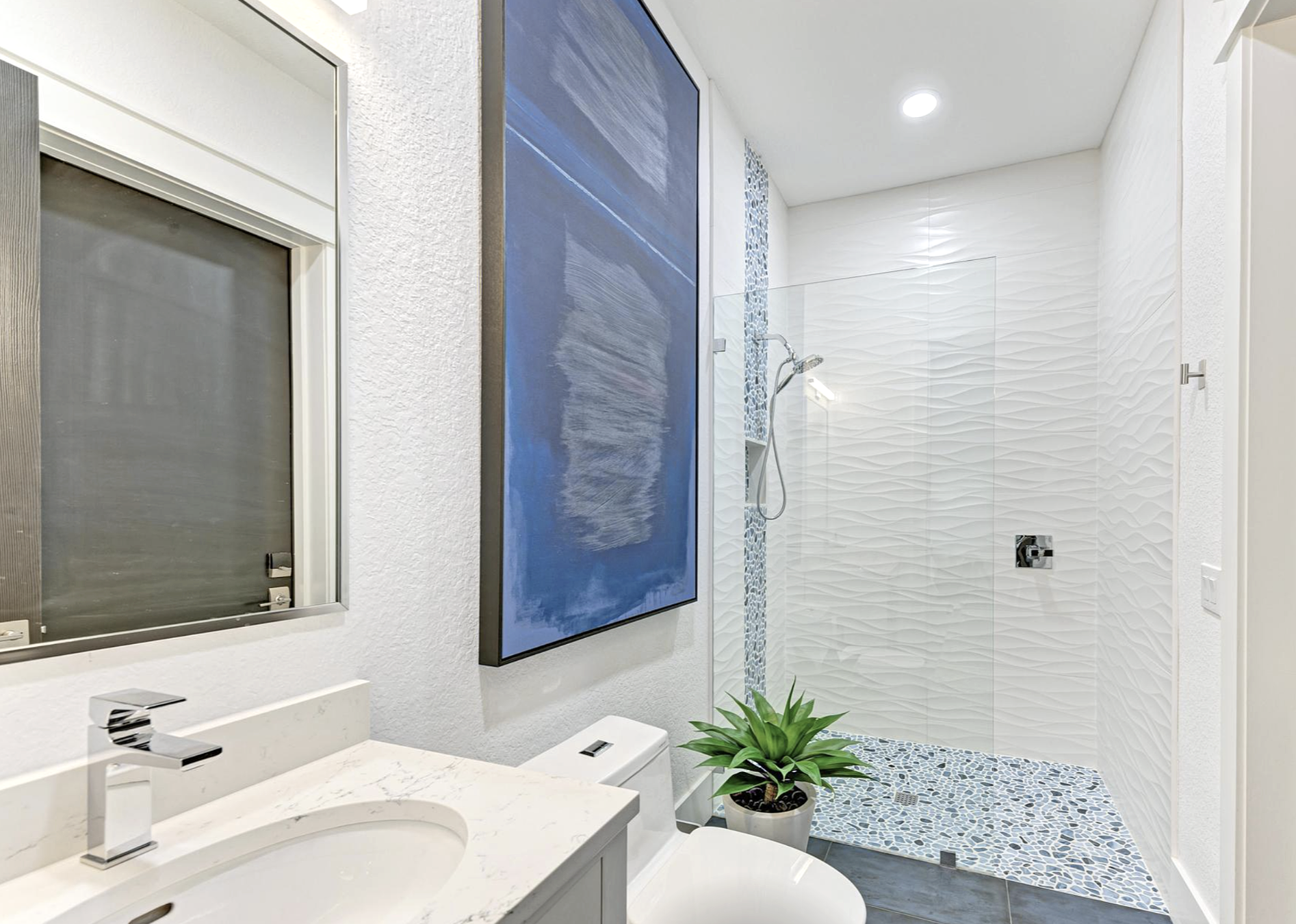Lakewood Ranch pool cabana bathroom remodel featuring an infinity shower with blue decorative glass tile panel, contemporary finishes, and spa inspired design