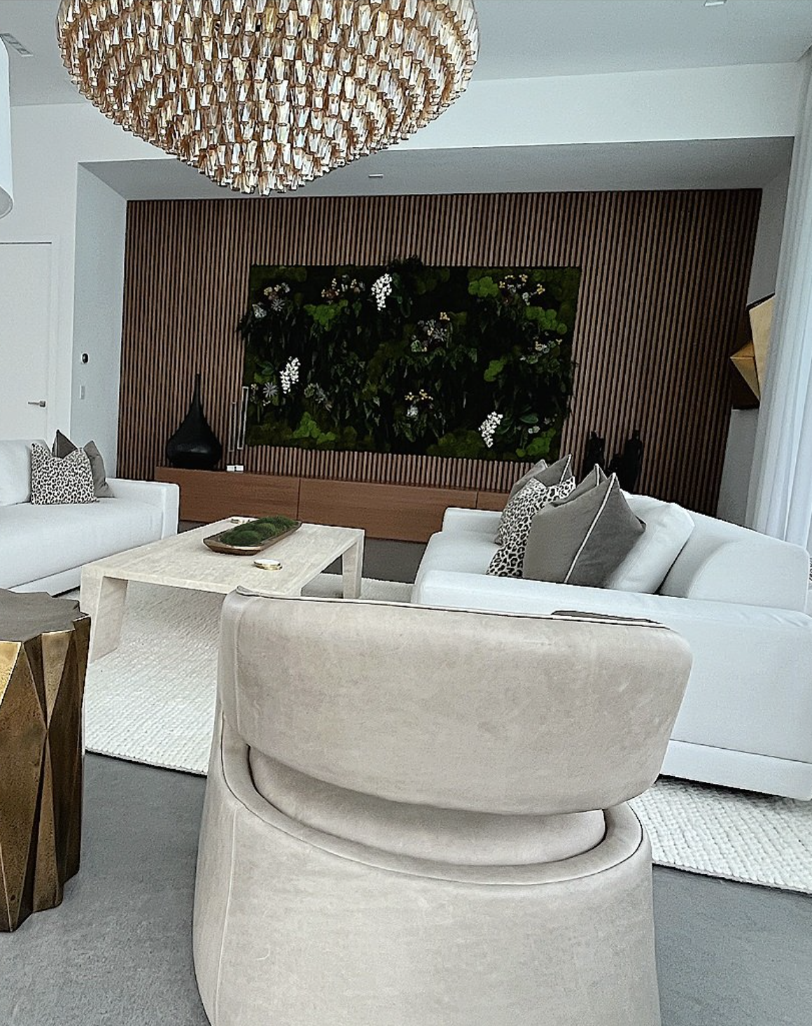 Contemporary living room interior design on Hibiscus Island Miami Beach featuring vertical wood slat wall, preserved plant wall, travertine table, and organic wool and leather furnishings