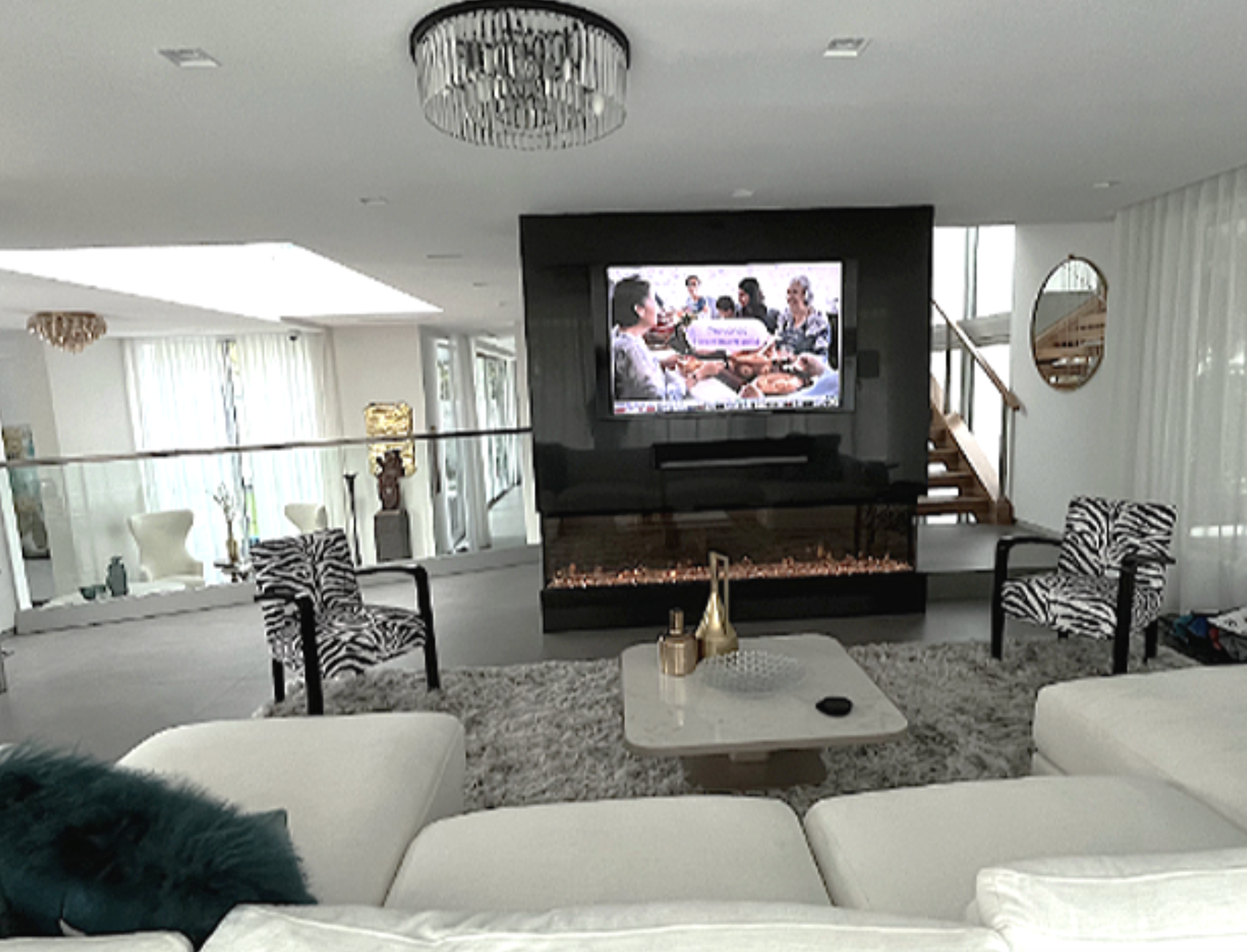 Hibiscus Island Miami Beach family room centered on a custom media wall with integrated fireplace, vintage French zebra chairs, and sculptural seating, transforming an empty contemporary space into an eclectic and casual TV lounge for family living