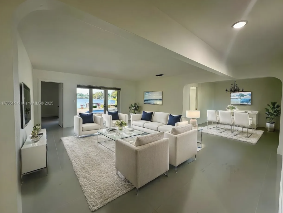 Before image of Miami vacation rental living room with white seating, open layout, waterfront view, and original pre-decorating design.