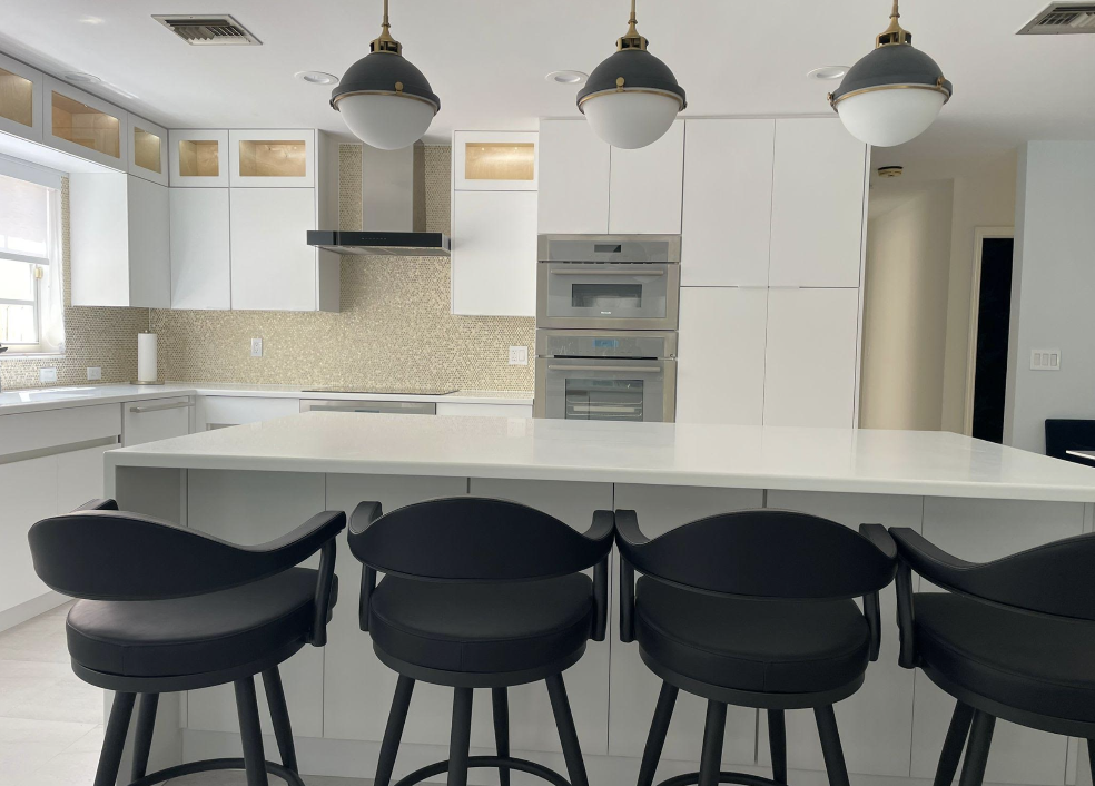Modern white kitchen with waterfall island, gold mosaic backsplash, and custom organizer cabinetry in Coconut Grove Miami home remodel by Exclusively To Design.