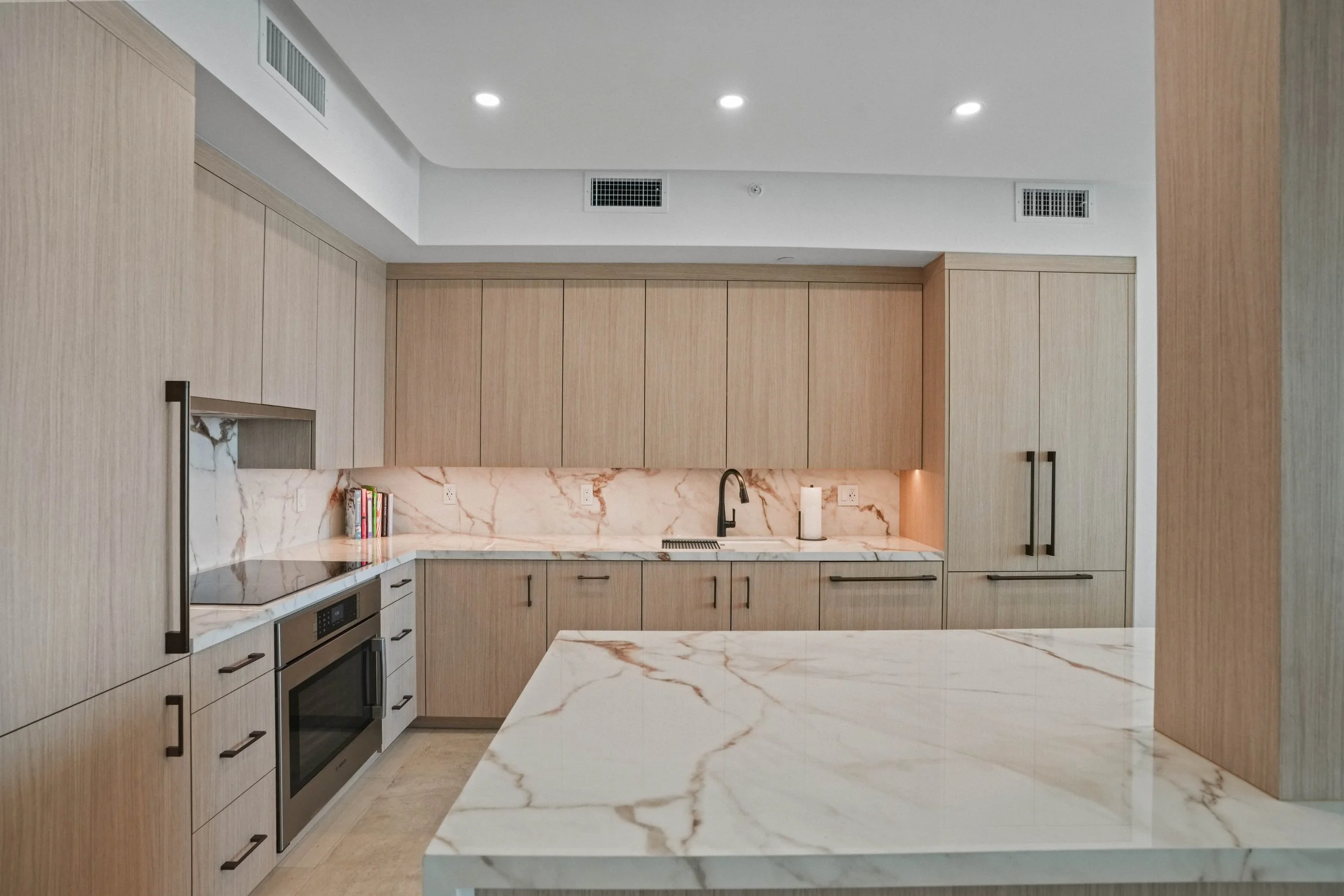 Hillsboro Beach kitchen with white oak cabinetry, marble surfaces, and integrated appliances