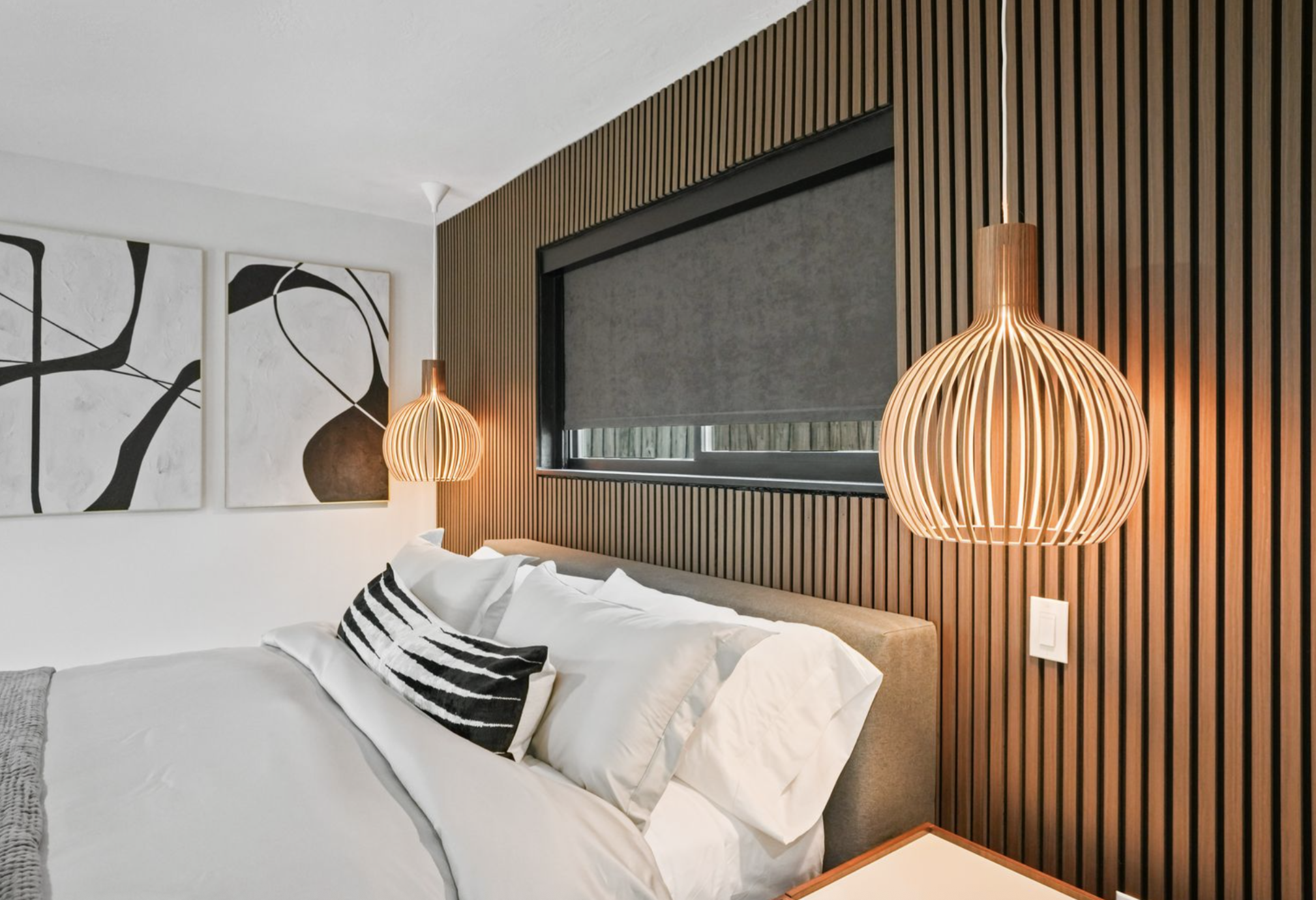 Master bedroom with walnut slat feature wall, pendant lighting, and tailored Italian bedding