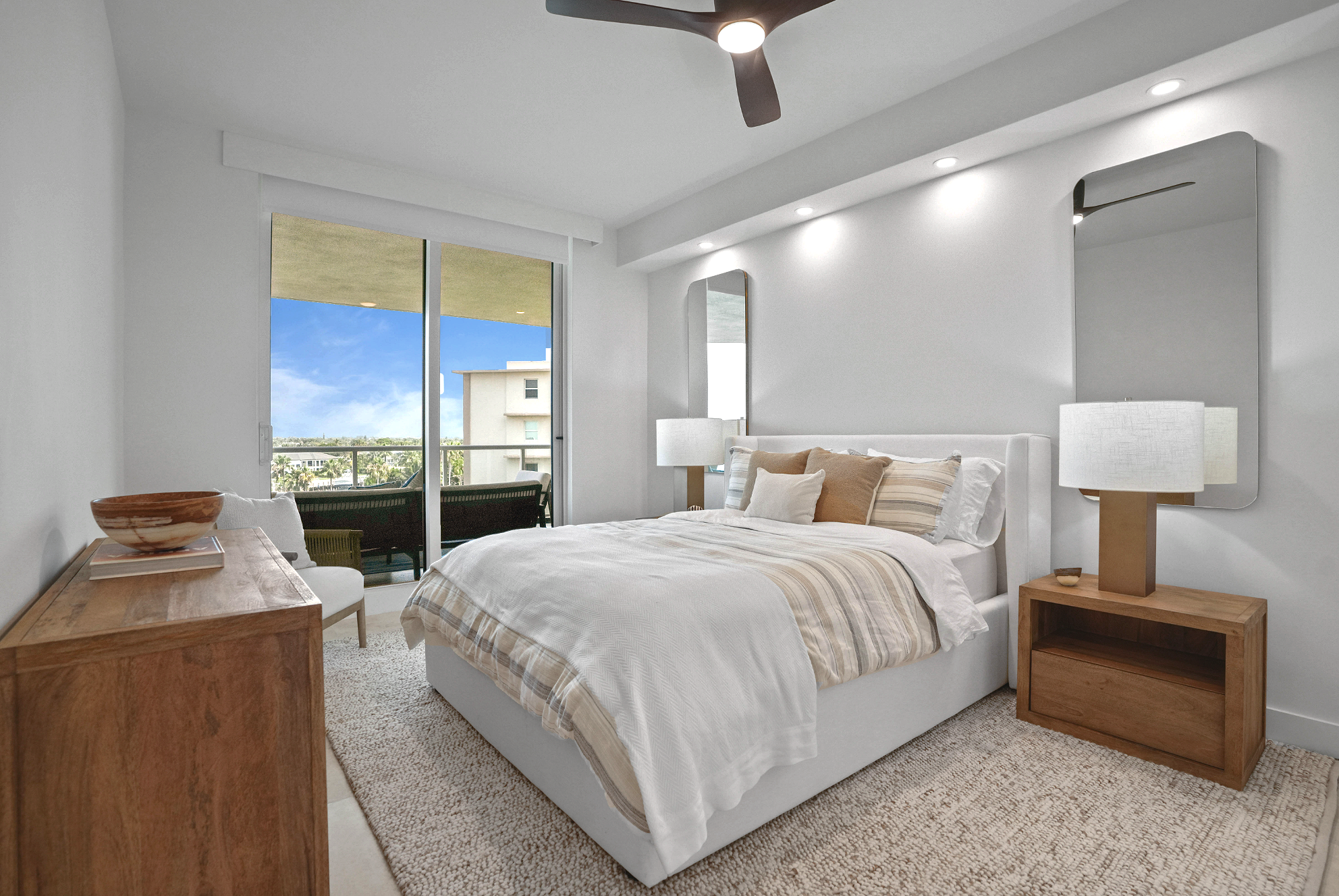 After organic coastal guest bedroom in a Hillsboro Beach luxury condominium featuring custom walnut furnishings, layered neutral bedding, integrated bedside lighting, and a warm organic coastal design with Intracoastal water views.