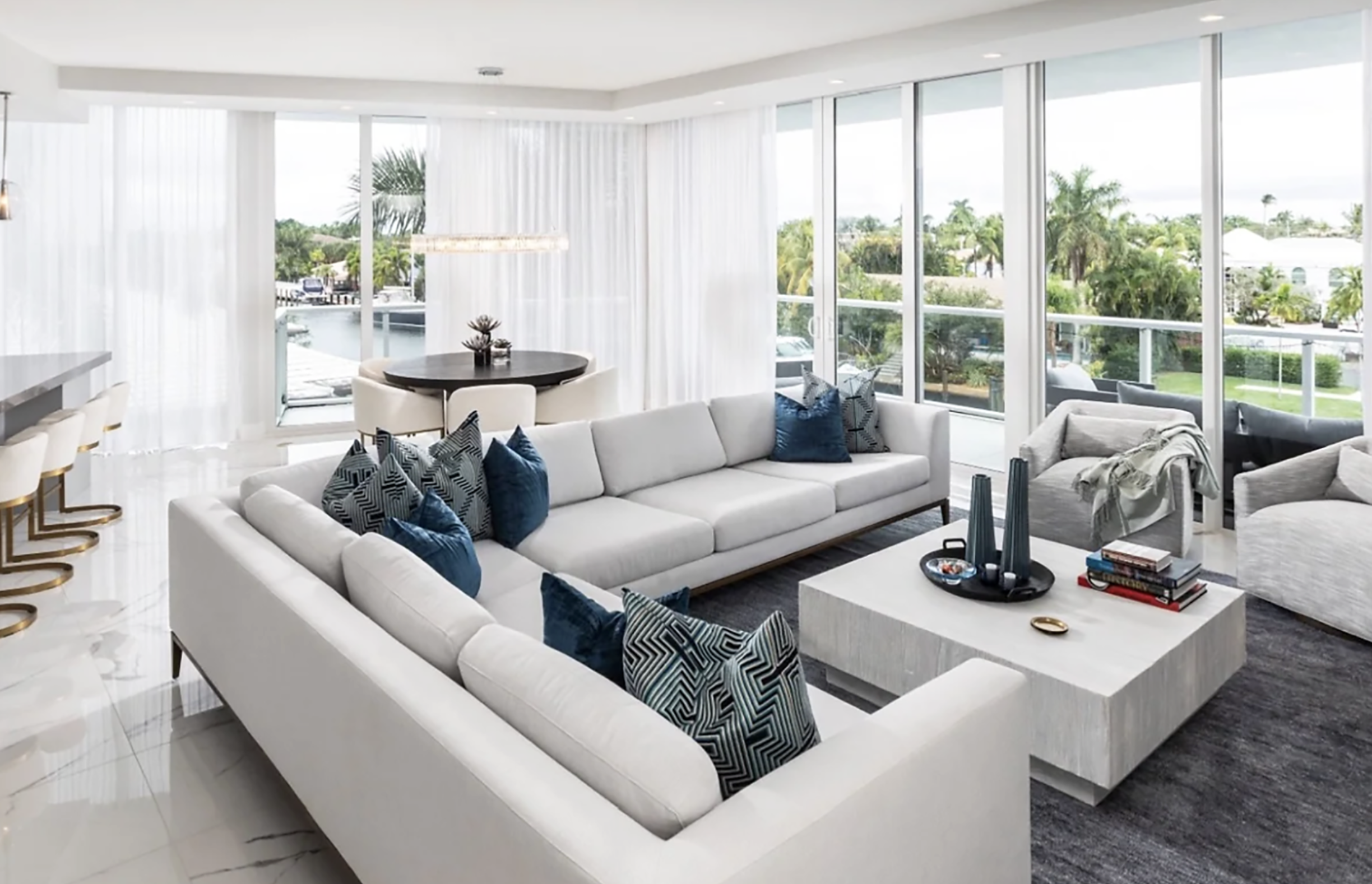 Bright contemporary white sectional layout and luxury interior styling for an urban waterfront penthouse living room in South Florida.⁠