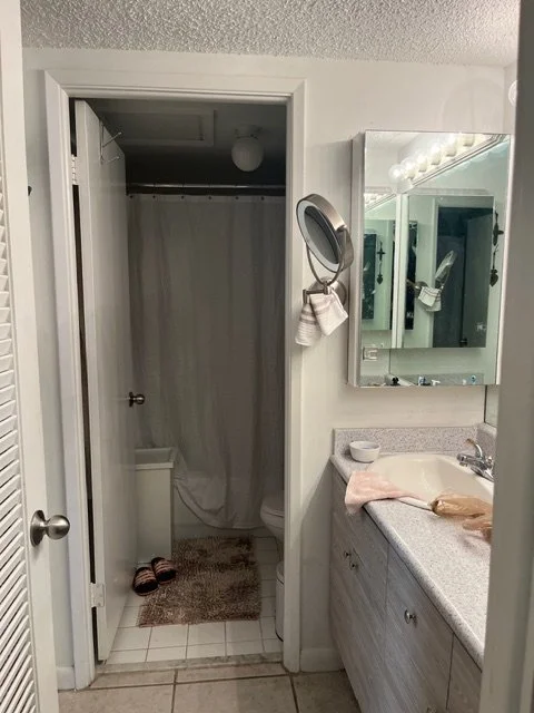 Before bathroom remodel in Miami Beach condominium showing original small vanity and shower layout prior to interior design renovation