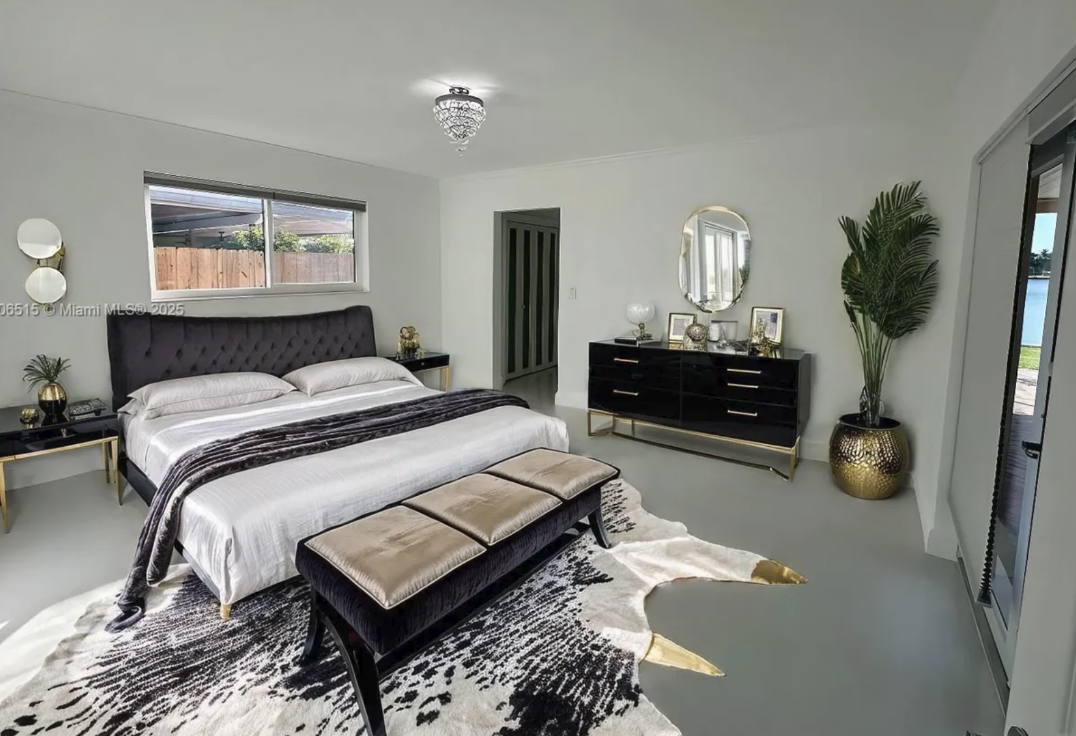 Before image of primary suite in Miami vacation rental with neutral furnishings, leather bench, and original pre-decorating layout.