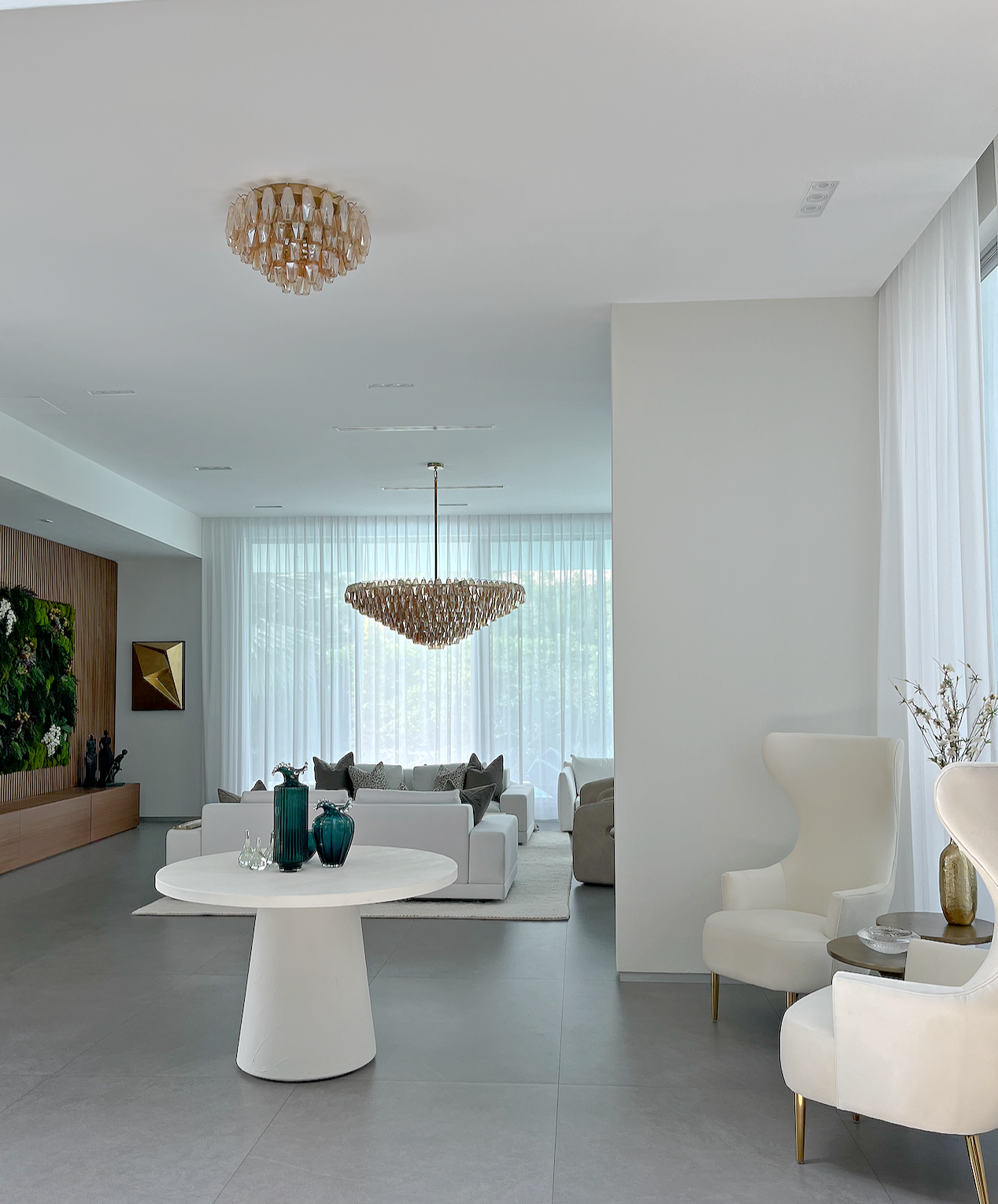 Miami Hibiscus Island luxury home remodeling interior entrance foyer featuring custom console table velvet wingback chairs and an open sightline looking toward a living room walnut slatted green moss wall⁠