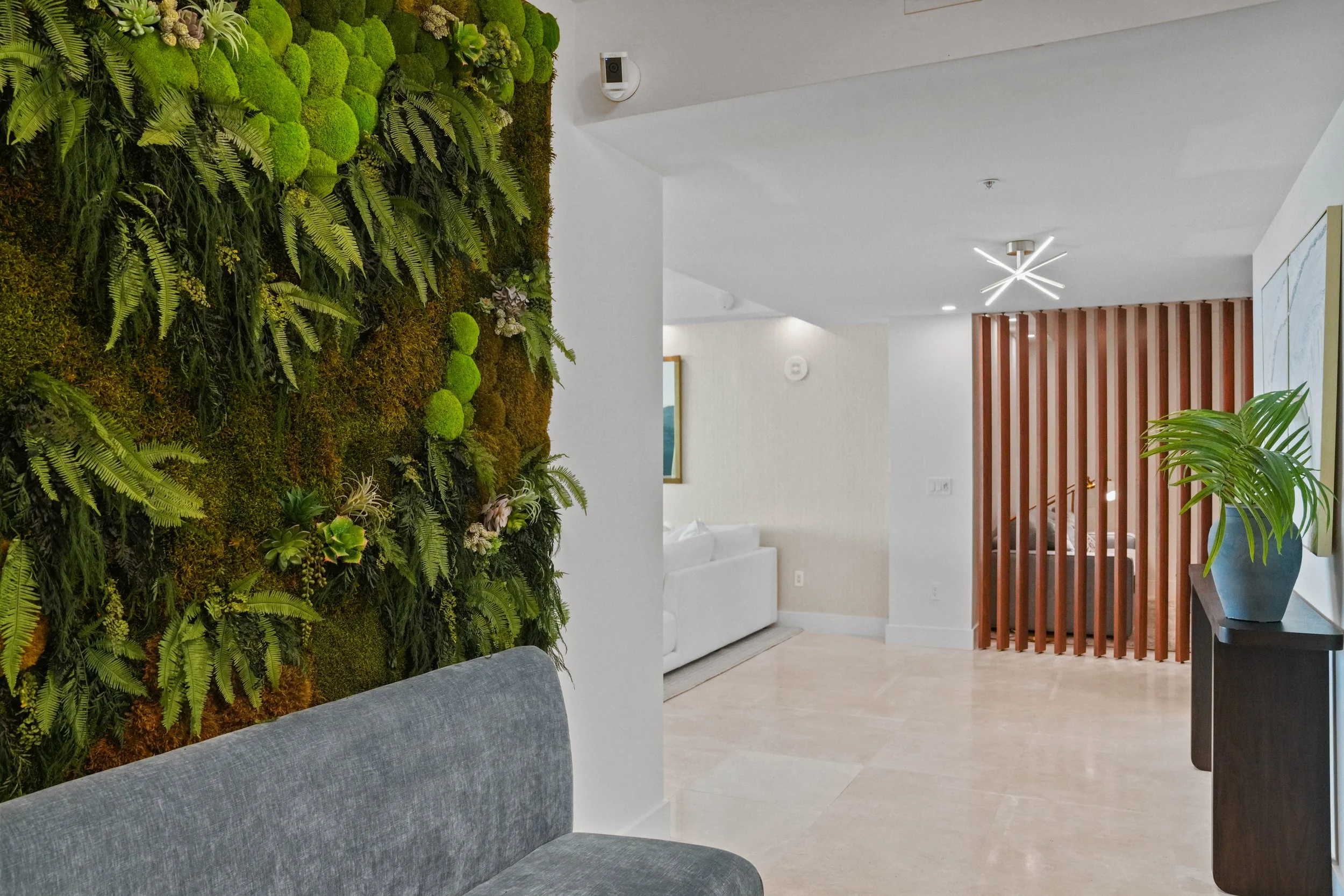 After luxury Hillsboro Beach condominium foyer remodel featuring an open elevator landing, preserved moss wall, custom bench seating, and unobstructed views into the waterfront residence.
