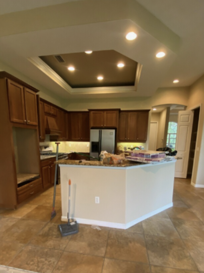 Lakewood Ranch kitchen before remodel with dark builder grade cabinetry, closed layout, recessed ceiling detail, and limited natural light