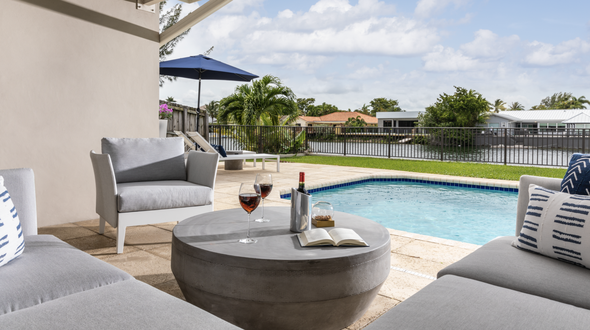 Conversational lounge and dining areas on a large pool deck in a ranch-style home in North Miami