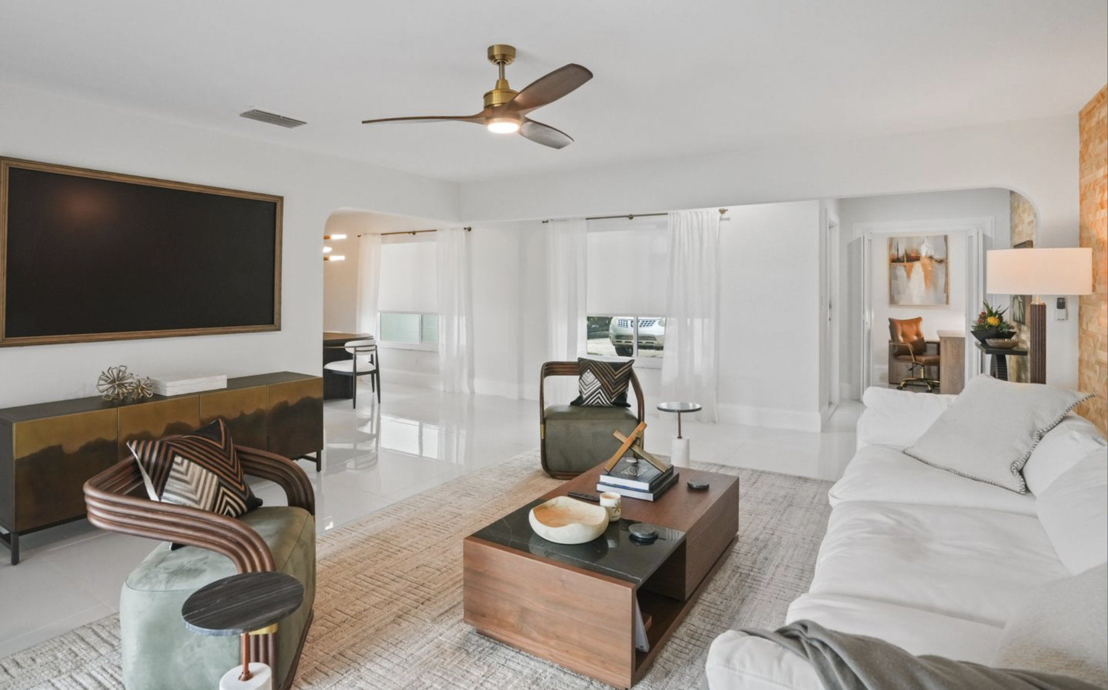Open living room in Miami vacation rental with white sofa, sculptural chairs, wood coffee table, media console, and turnkey Tulum-inspired styling.