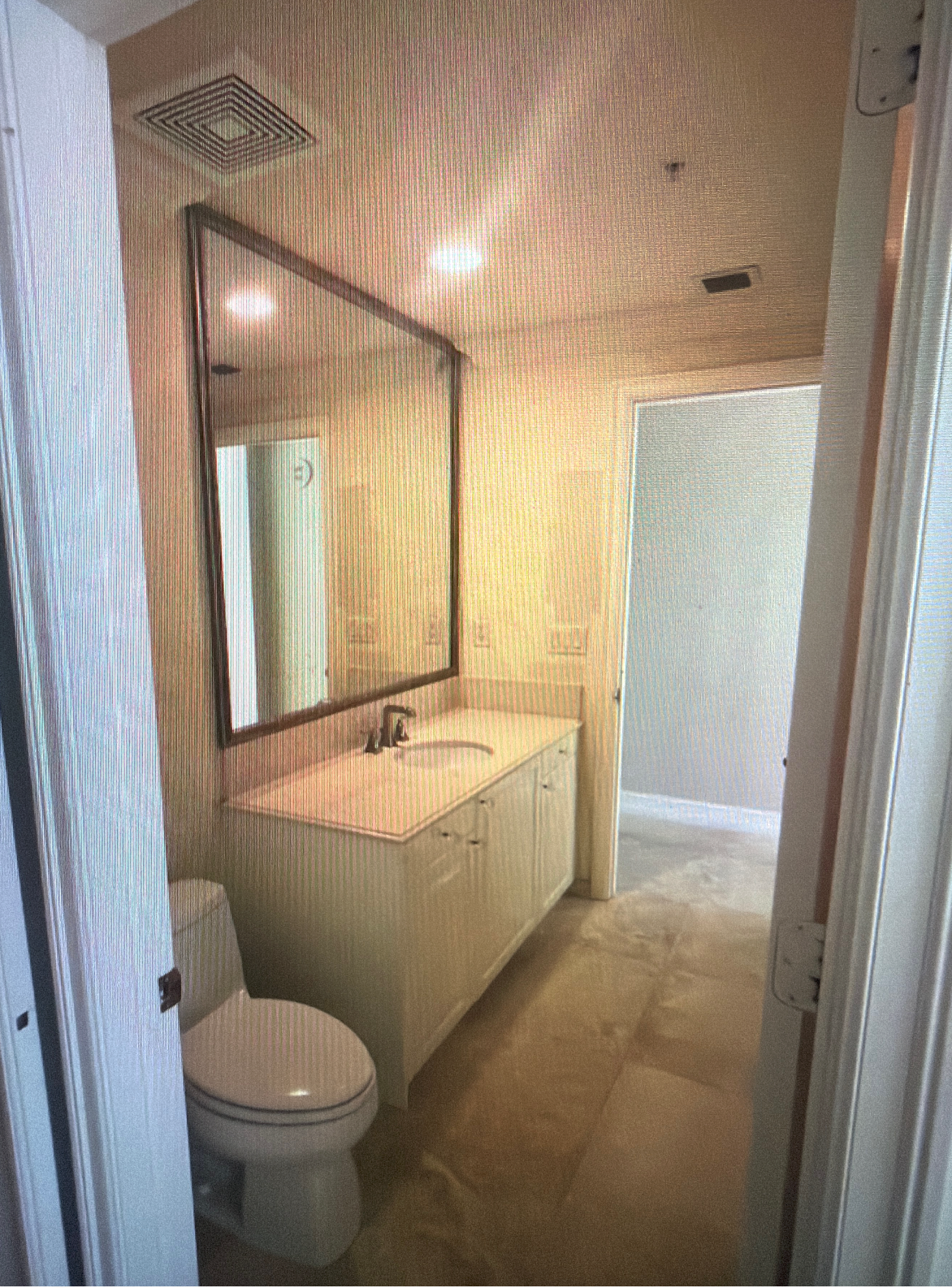 Before Jack-and-Jill guest bathroom in a Hillsboro Beach condominium featuring an outdated vanity, swing door, enclosed shower, and builder-grade finishes before luxury renovation.
