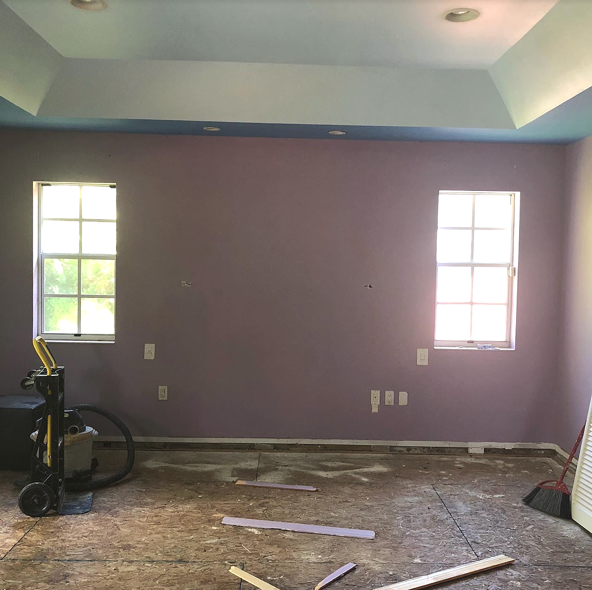 Dated luxury estate master bedroom before an interior design remodel by Exclusively to Design featuring an uninspired purple accent wall and basic tray ceiling layout.