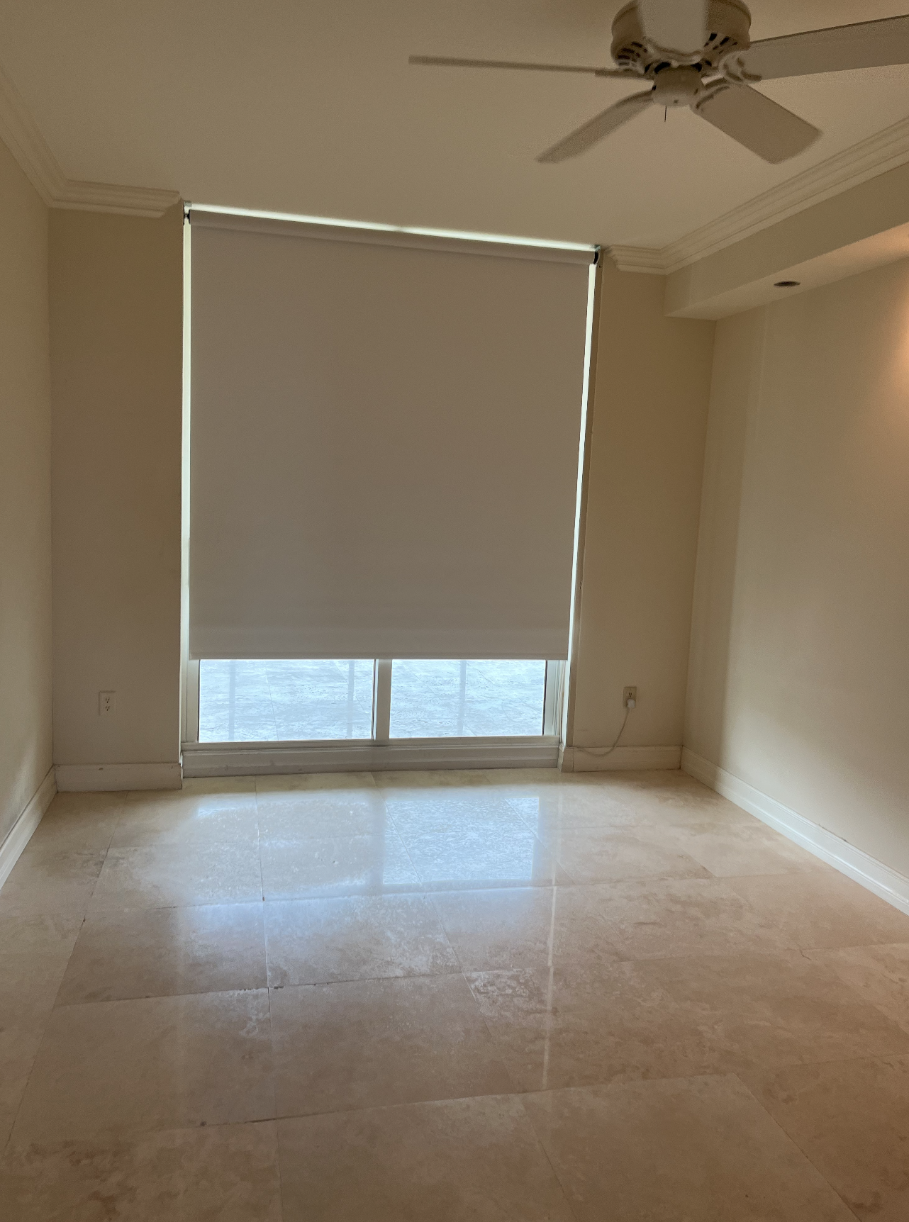 Before organic coastal guest bedroom in a Hillsboro Beach condominium with empty marble floors, roller shade, and an unfinished layout before luxury interior design renovation.