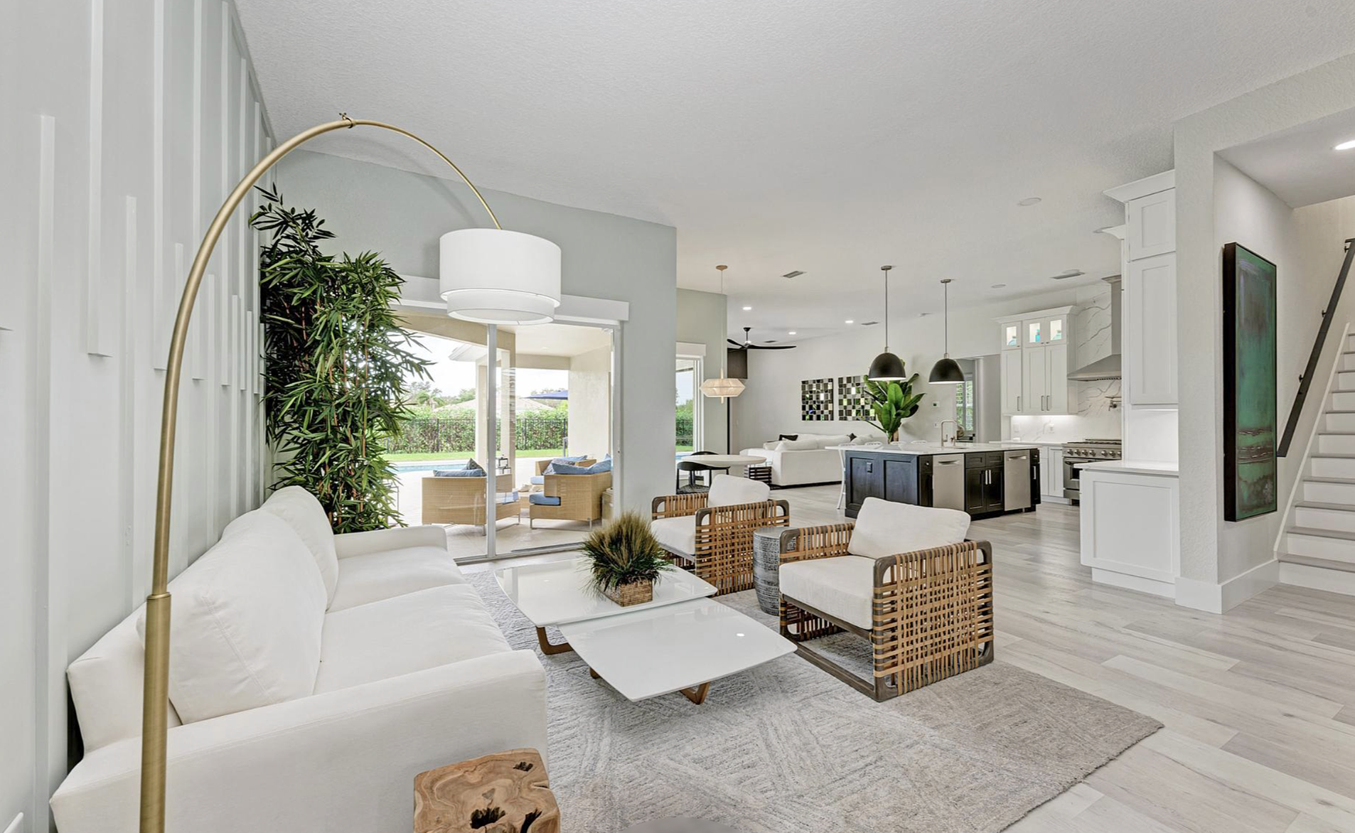 Open-concept home remodeling in Lakewood Ranch by Exclusively to Design featuring a pale aqua accent wall with vertical wood detailing, coastal high-performance fabric furniture, a modern kitchen island layout, and light gray flooring.