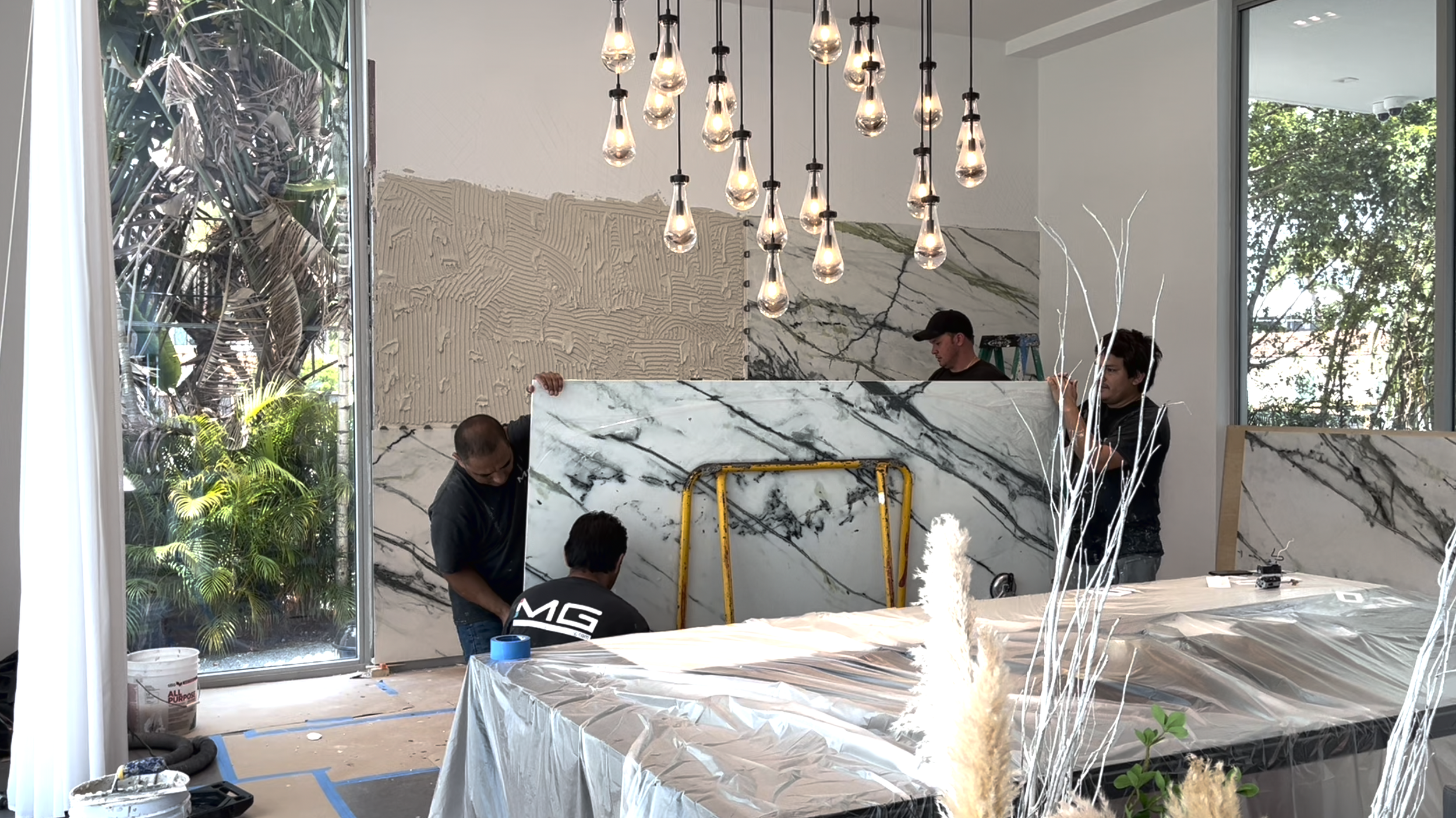 Green Calacatta porcelain slab feature wall installation in dining room during renovation of Hibiscus Island Miami Beach luxury residence