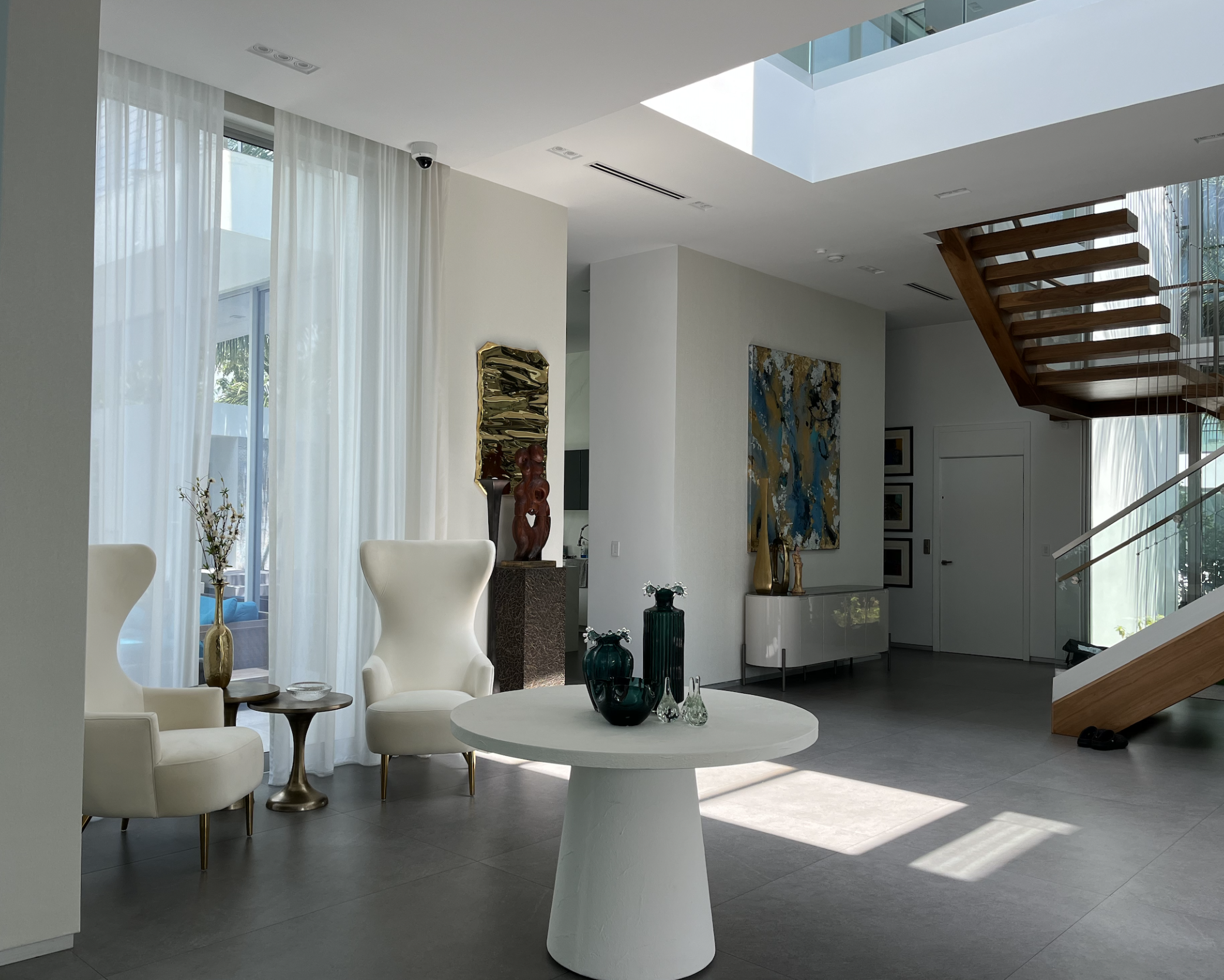 Hibiscus Island Miami Beach contemporary foyer with double height ceilings, sheer drapery, sculptural seating, and curated personal art collection, designed to soften a large scale modern interior and introduce warmth and individuality