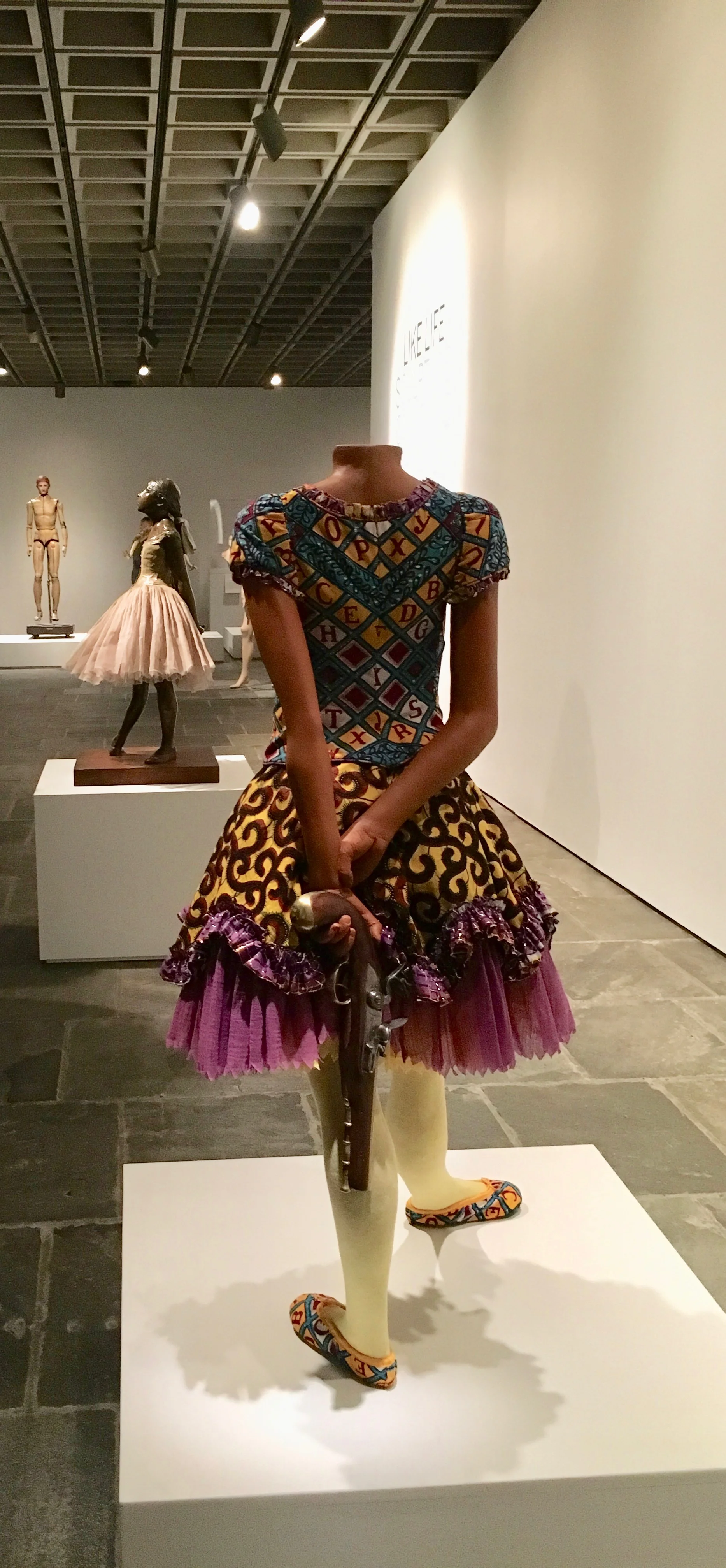 Yinka Shonibare MBE's “Girl Ballerina” (2007) stalks Edgar Degas’s famous bronze “Little Fourteen-Year-Old Dancer” (1881).