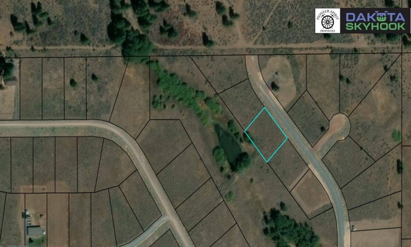 Aerial view of a subdivision with multiple plots of land, roads, and some trees, including a highlighted plot outlined in turquoise.